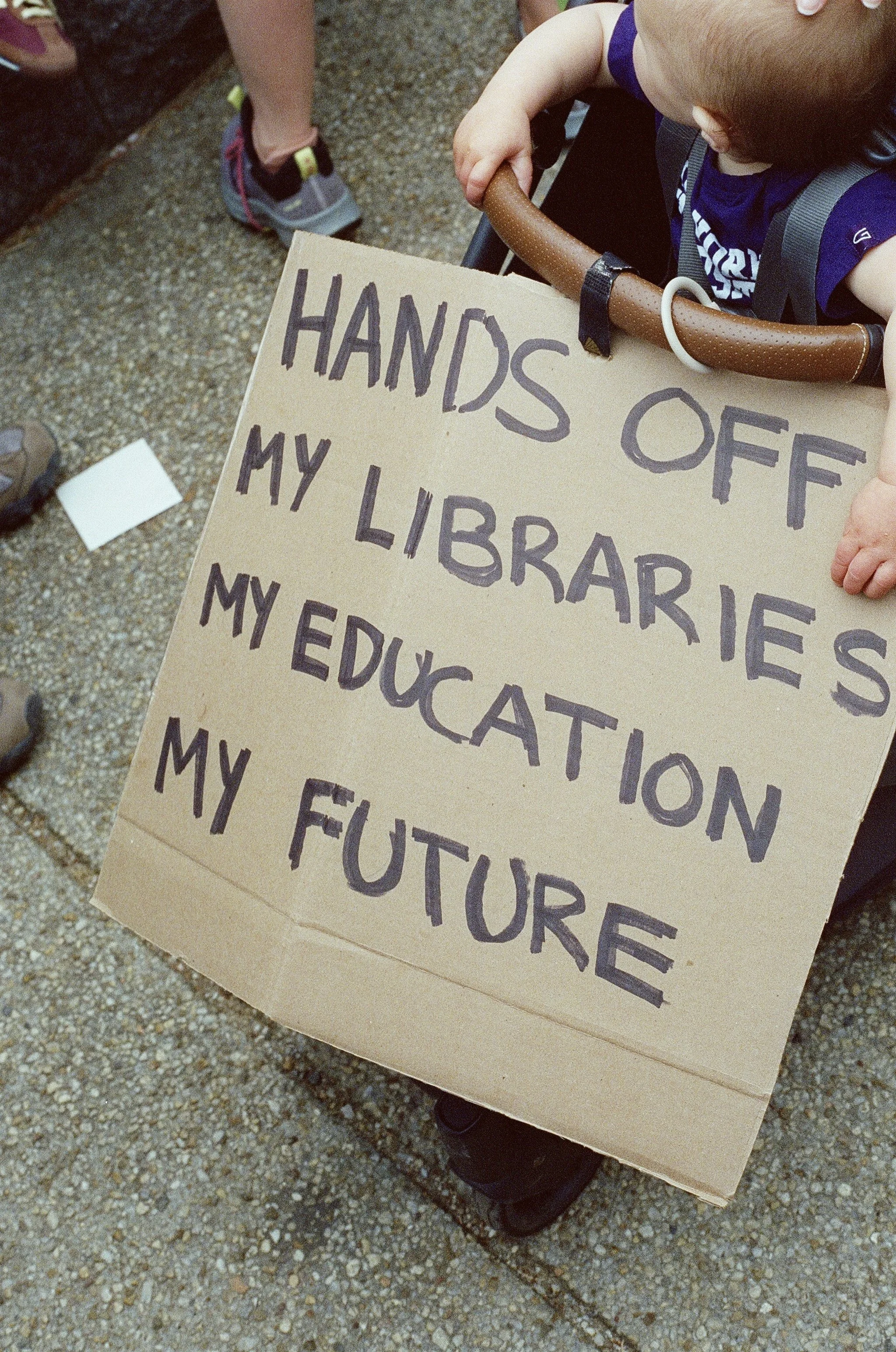 A baby with a sign proclaiming "hands off my future."