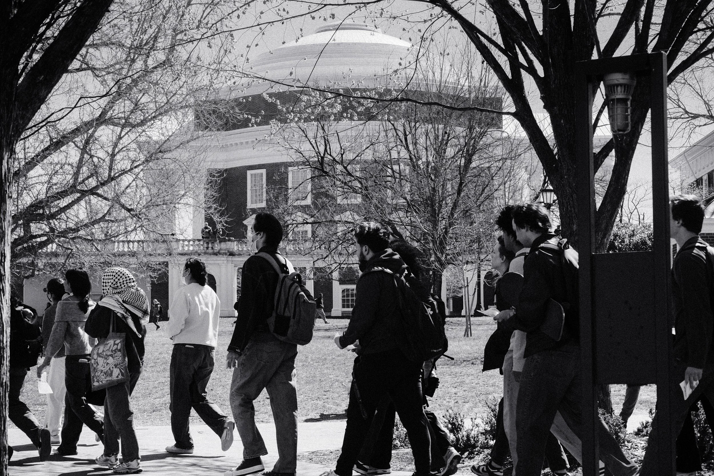 Students march in front of the Rotunda, while security watches from the balcony.