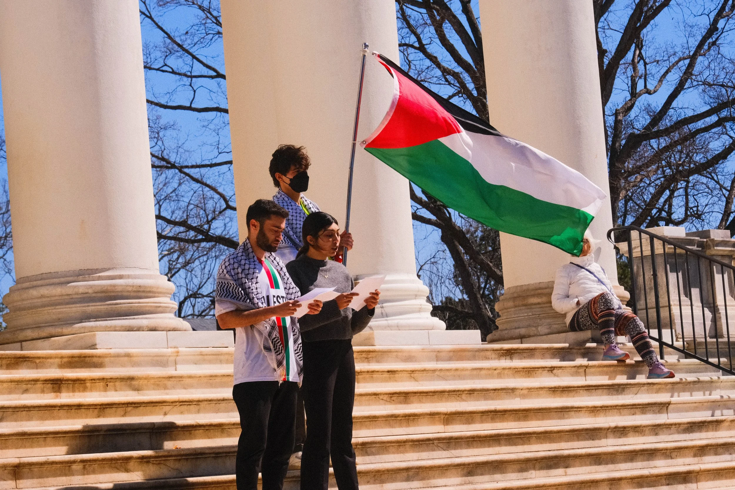 Students wielding a Palestinian flag on the steps of the Rotunda.