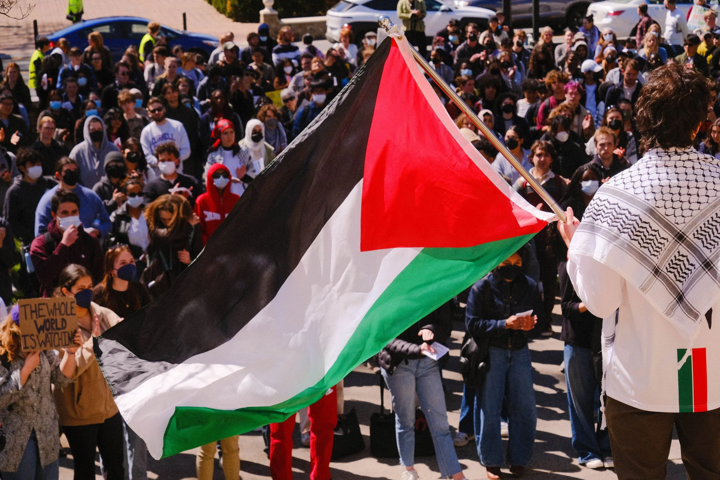 A student wields a Palestinian flag on the steps of a critical UVA office building.