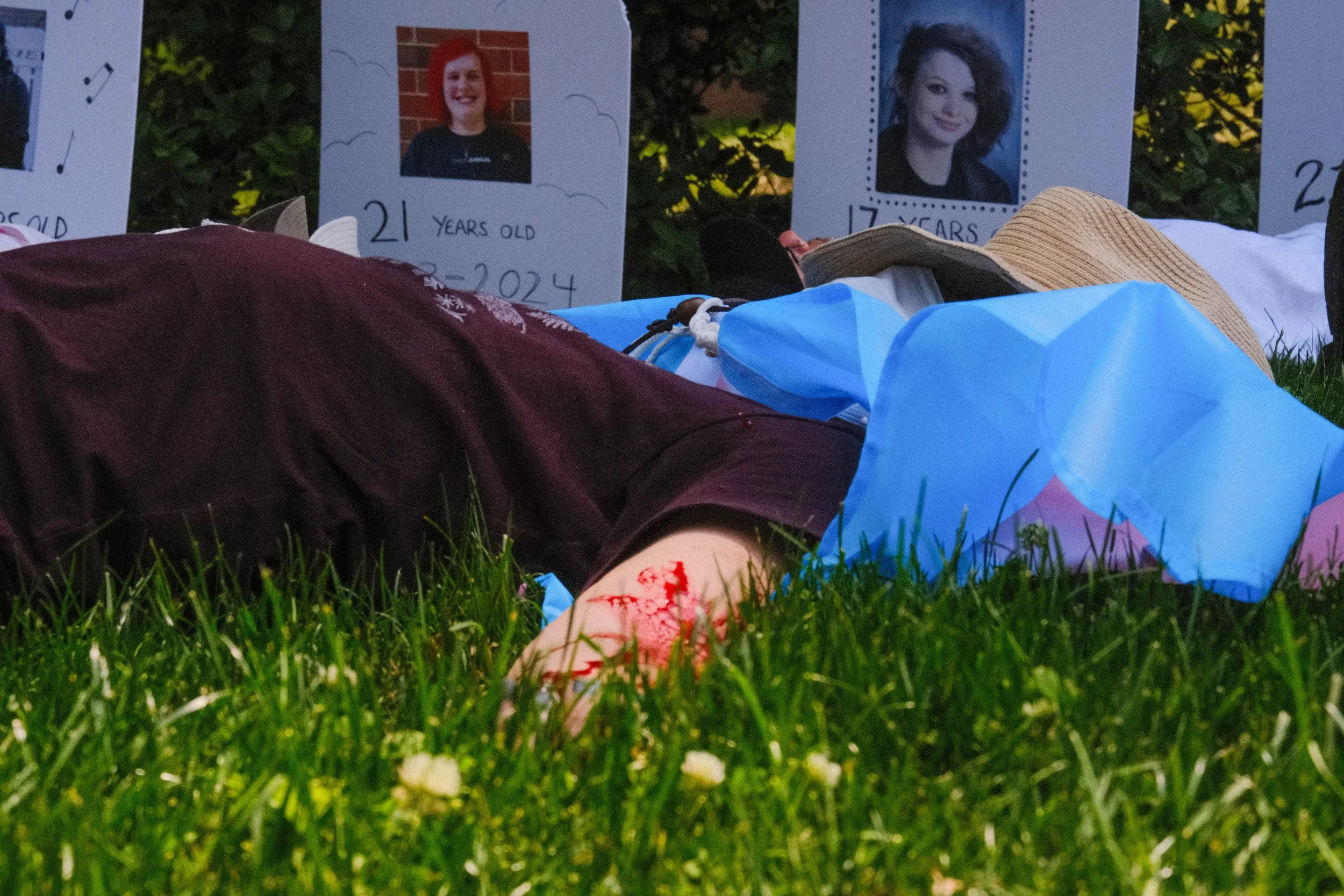 a woman lies with fake blood on her wrist, symbolizing transgender suicide.