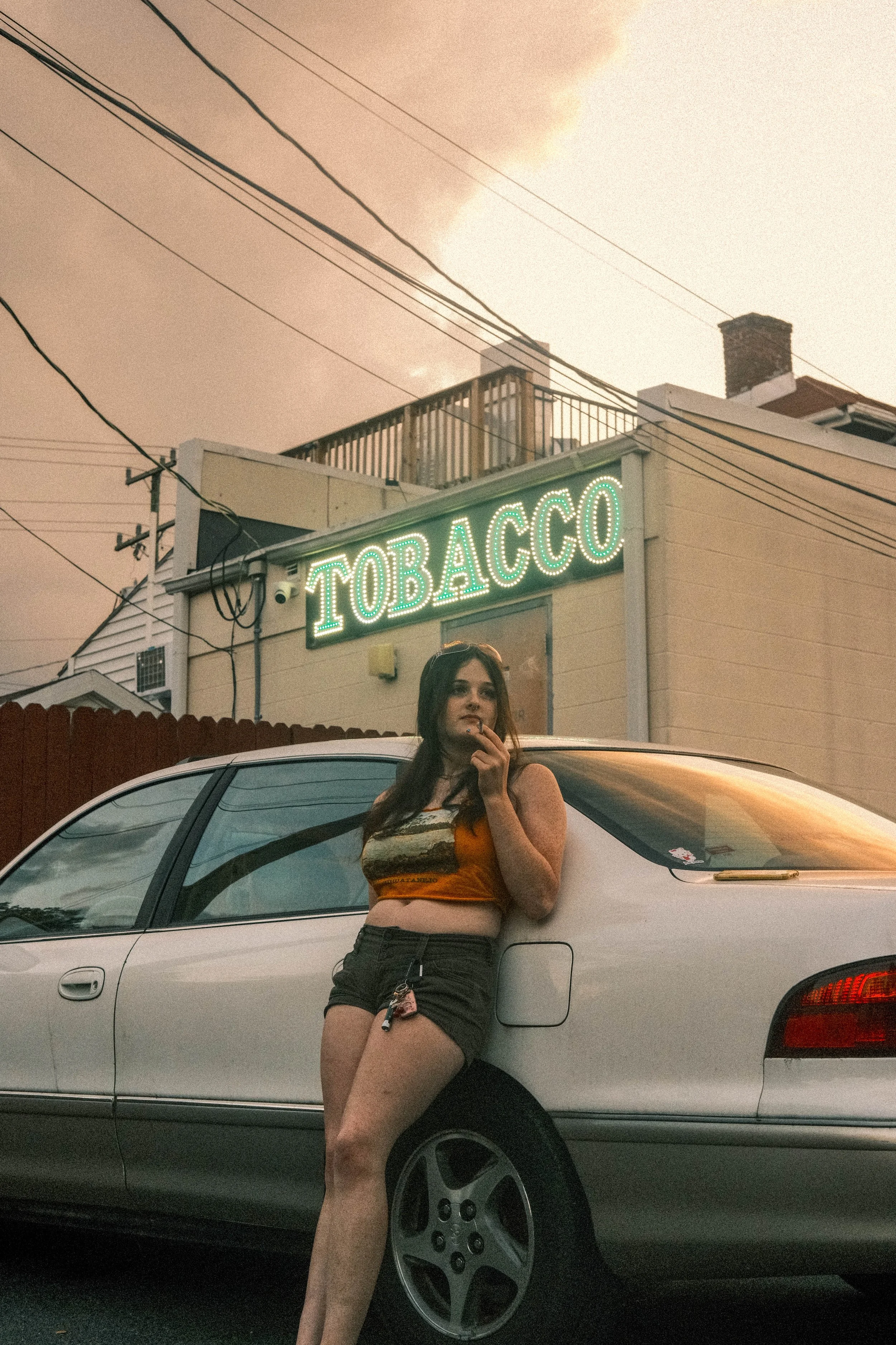 A friend stands outside a Tobacco shop smoking.