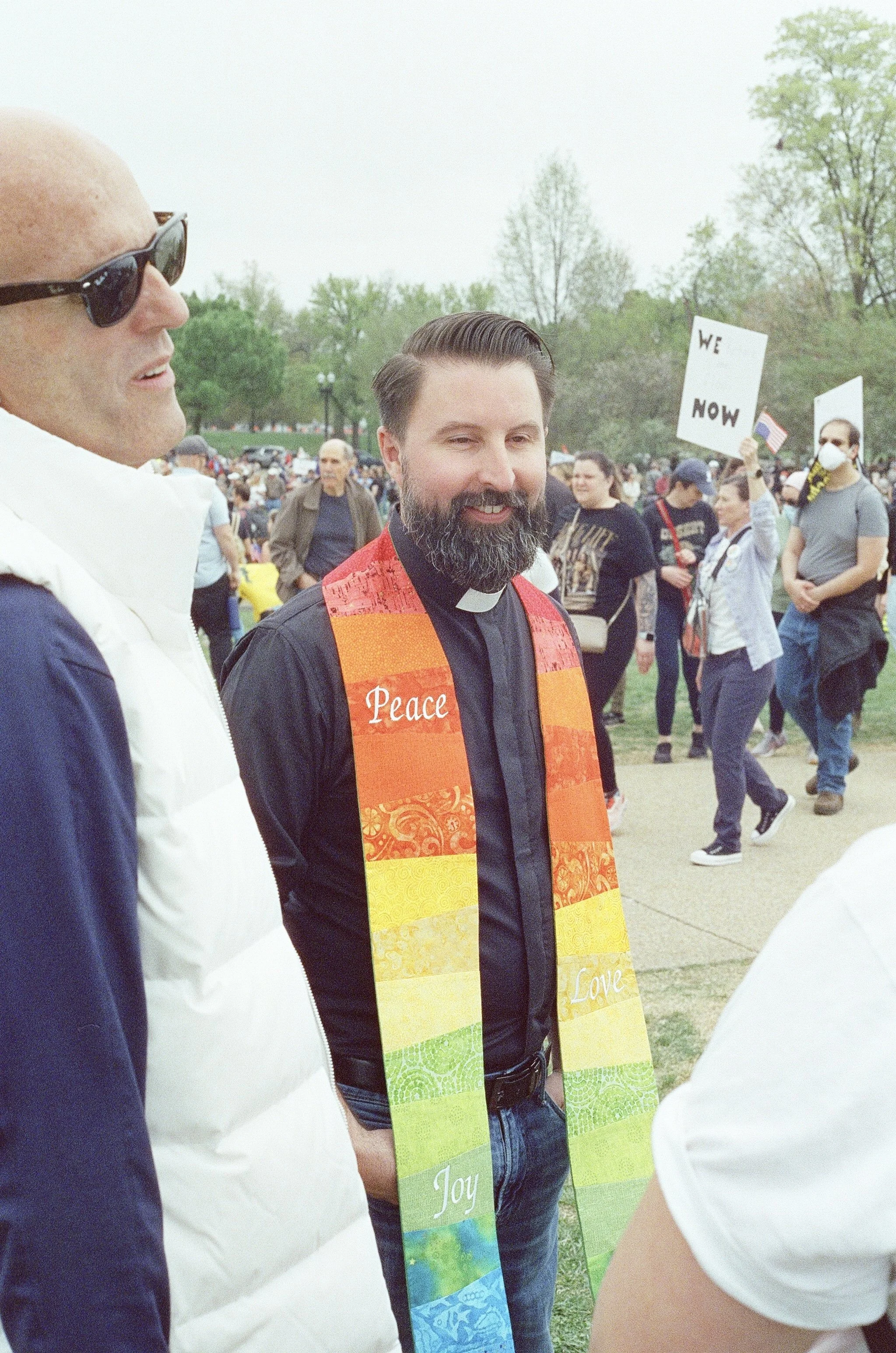 A priest with a pride sash.