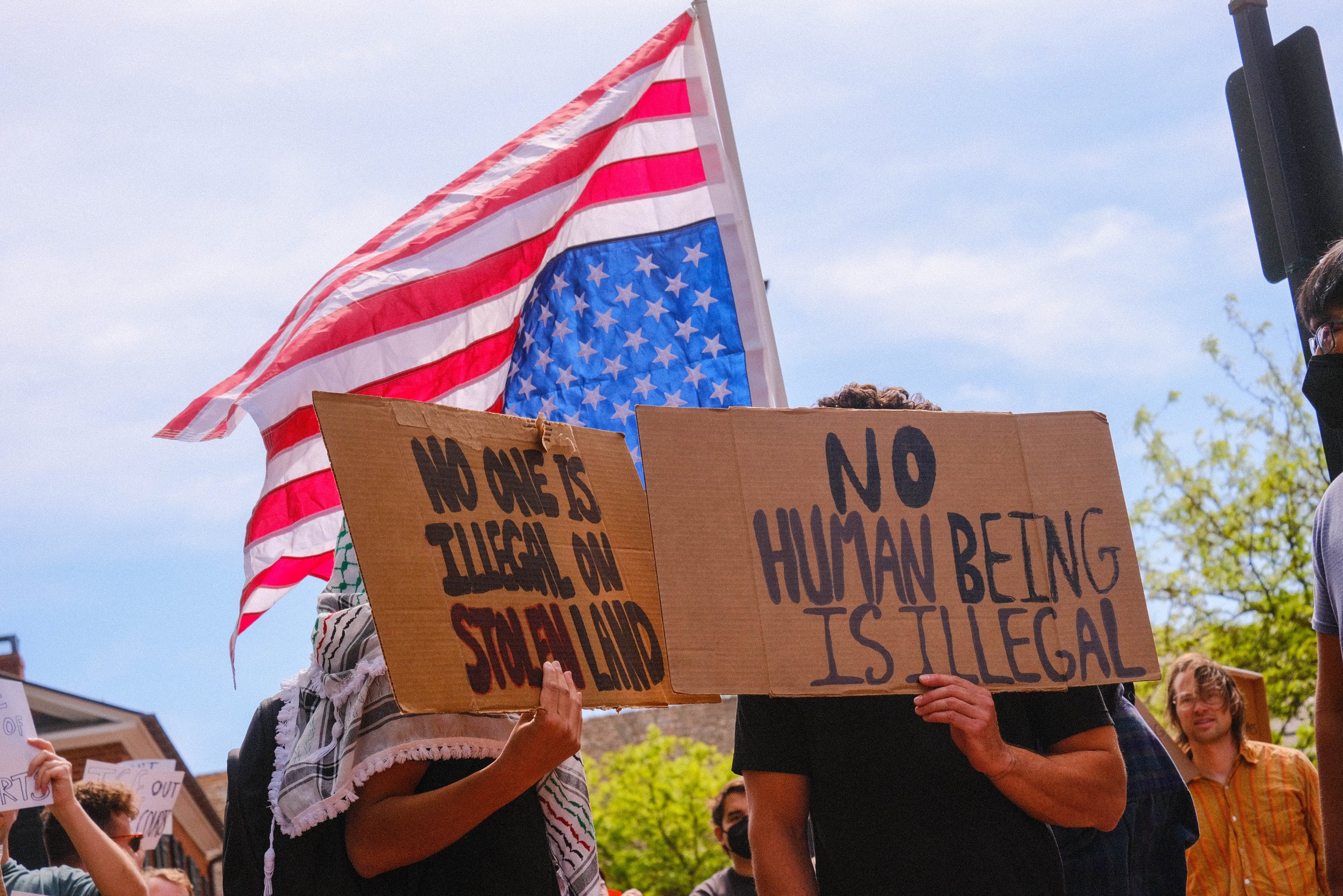Young hispanic protesters covering their faces with signs out of fear.