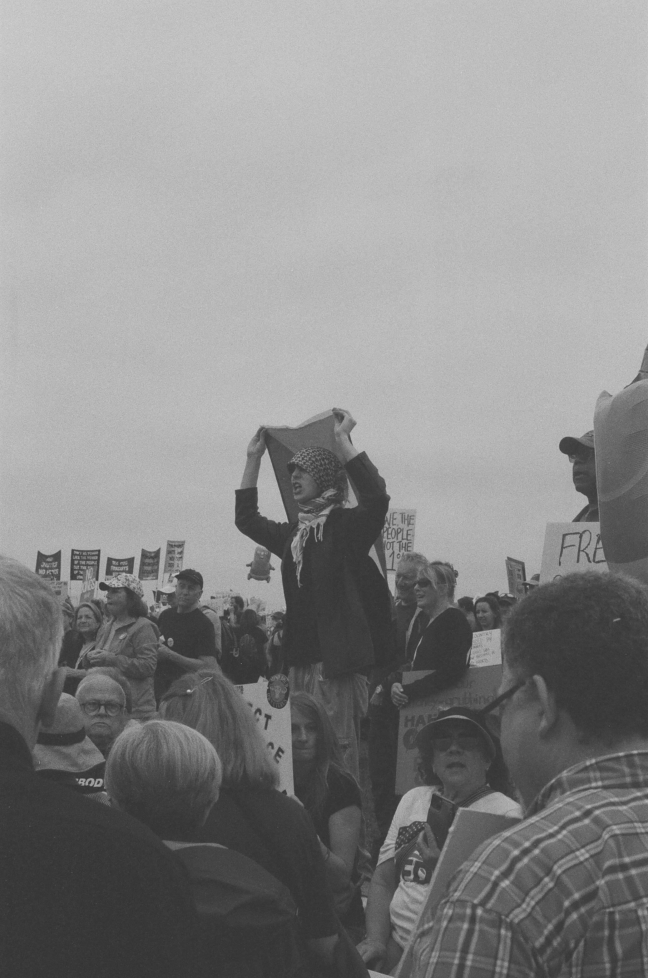 A protester in a keffiyeh holding a Palestinian flag.