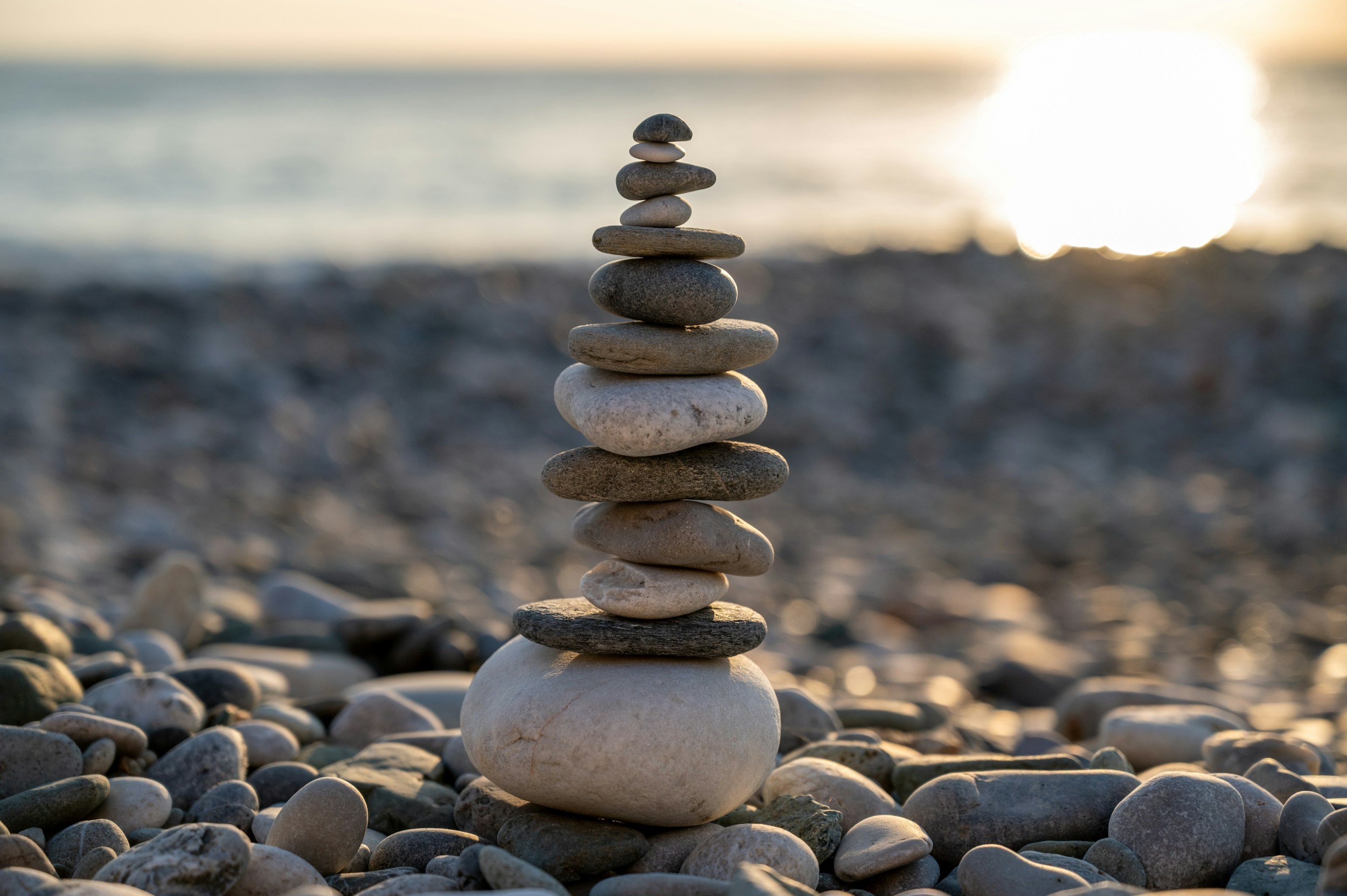 Stack of smooth ocean stones on a pebbly beach at sunset.