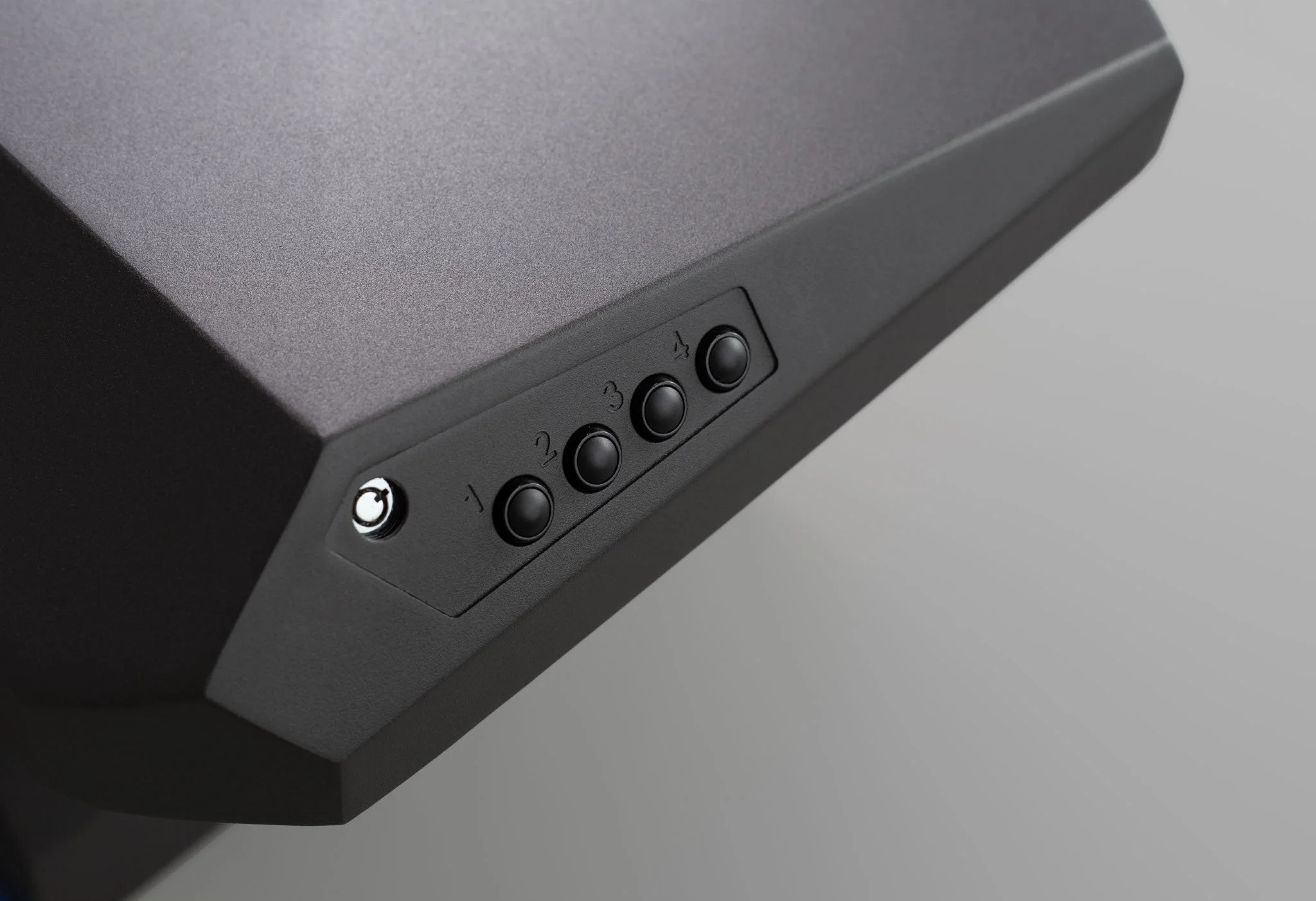 Close-up of a black electronic device with multiple round buttons and a small circular port.