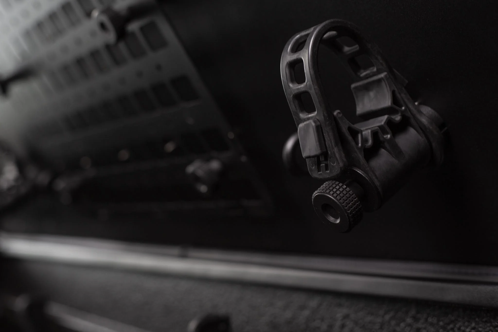 Close-up of a firearm's scope mount and Picatinny rail on a black firearm.