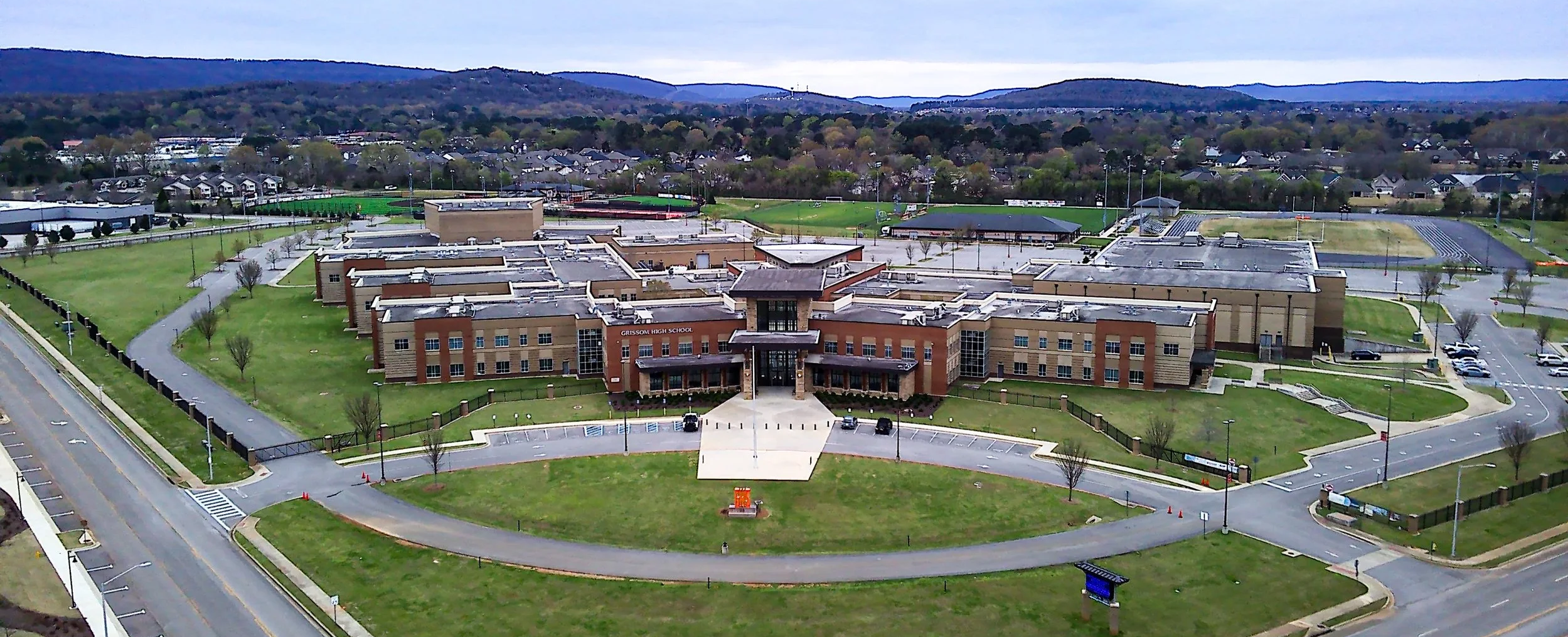 Aerial view of Grissom High School campus with multiple buildings, parking lots, athletic fields, and surrounding neighborhoods in the background.