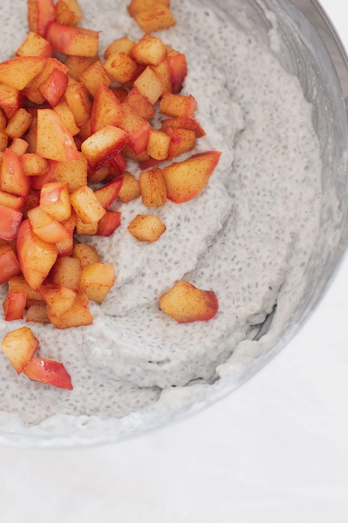 Apple pie chia pudding mixture with chia seeds and cinnamon apples in a large bowl.