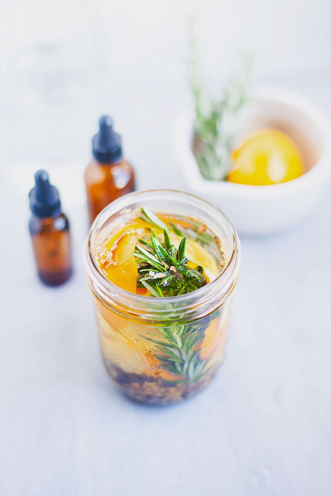 Close-up of digestive bitters in a mason jar with visible herbs and citrus peel.