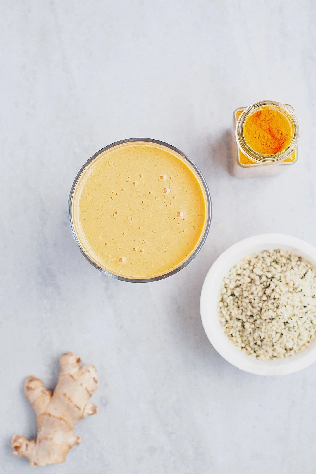 Ingredients for mango and turmeric smoothie for healthy digestion — mango, hemp seeds, ginger, and turmeric on a white background.