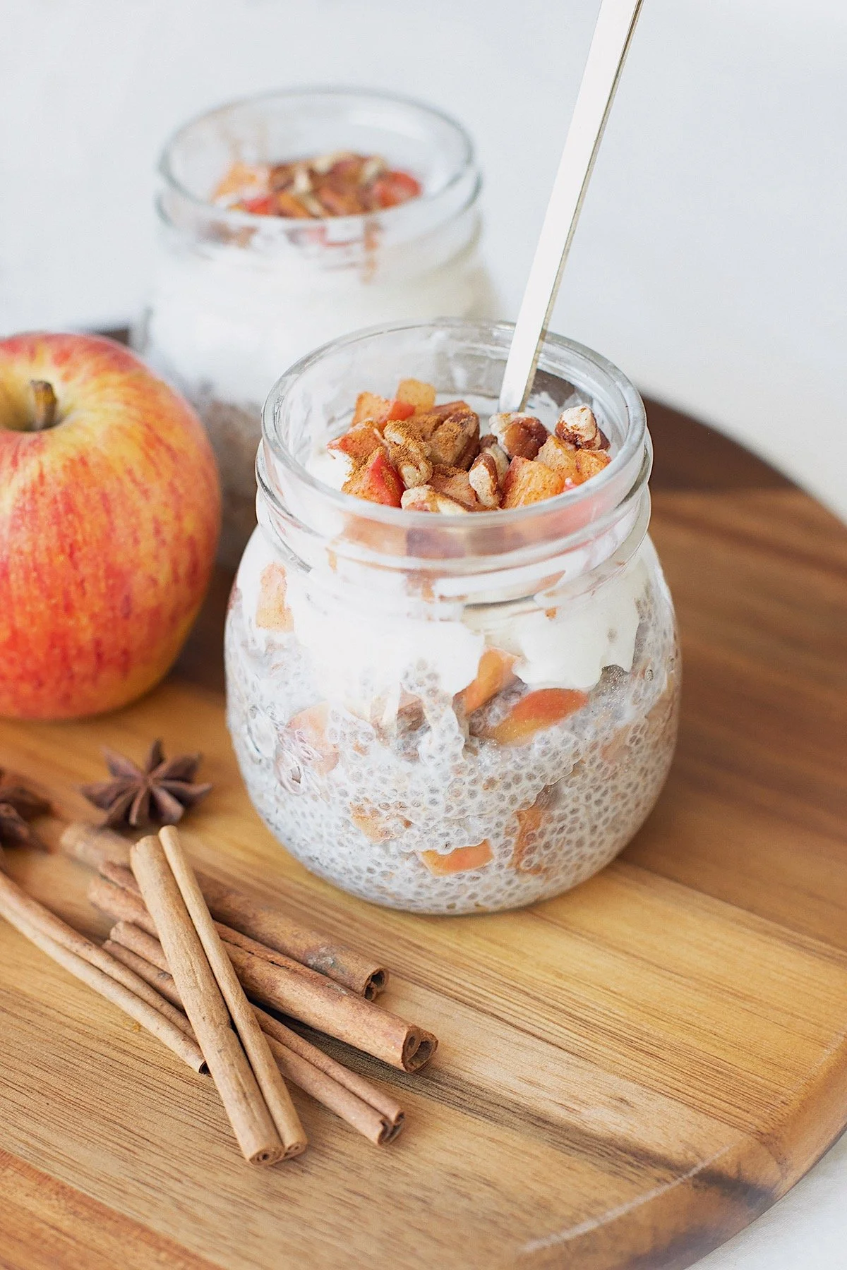Jar of apple pie chia pudding with cinnamon apples and pecans on top.