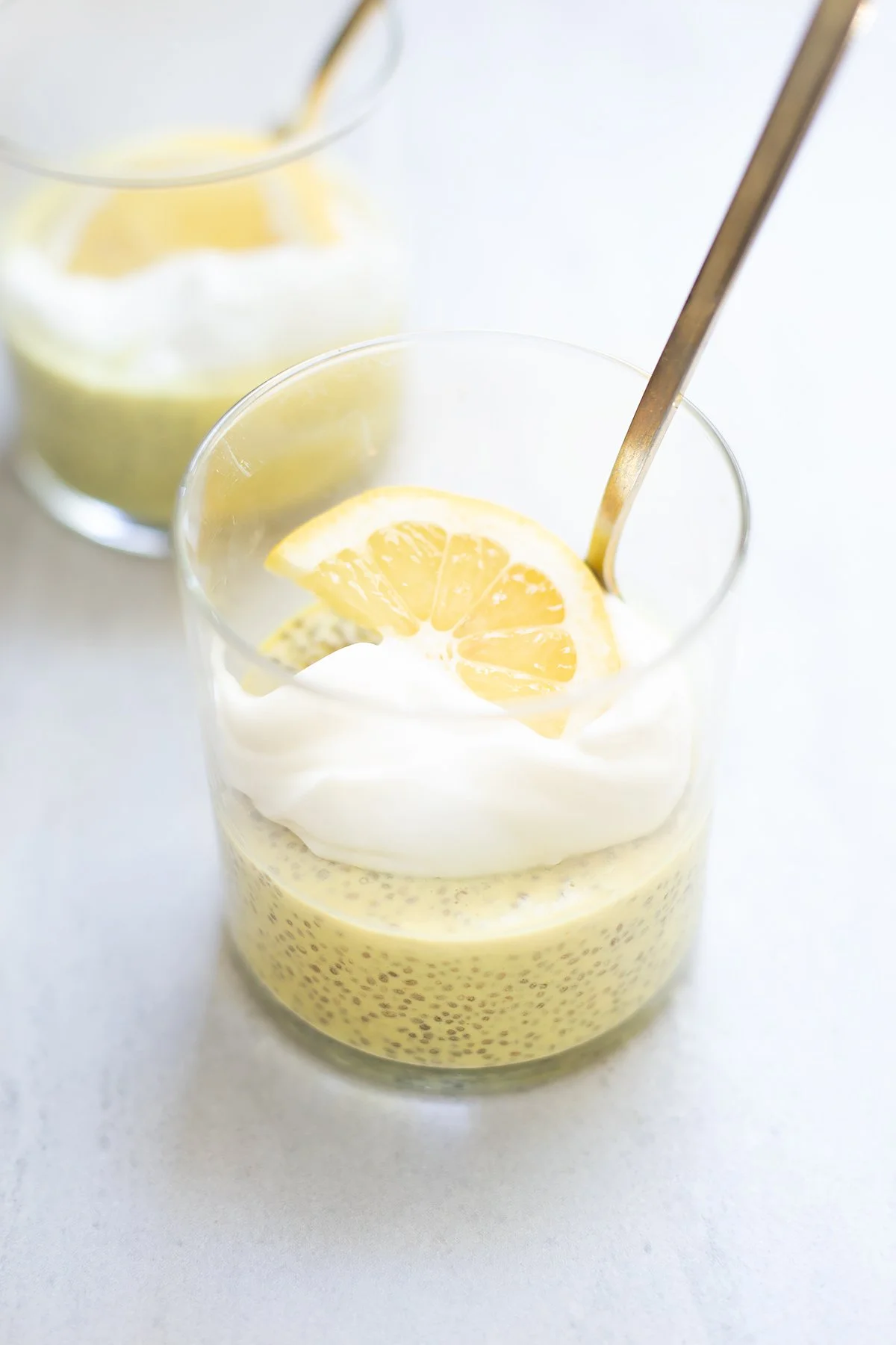 Two glasses of lemon chia seed pudding with spoons, layered with coconut yogurt for a creamy, dairy-free breakfast.