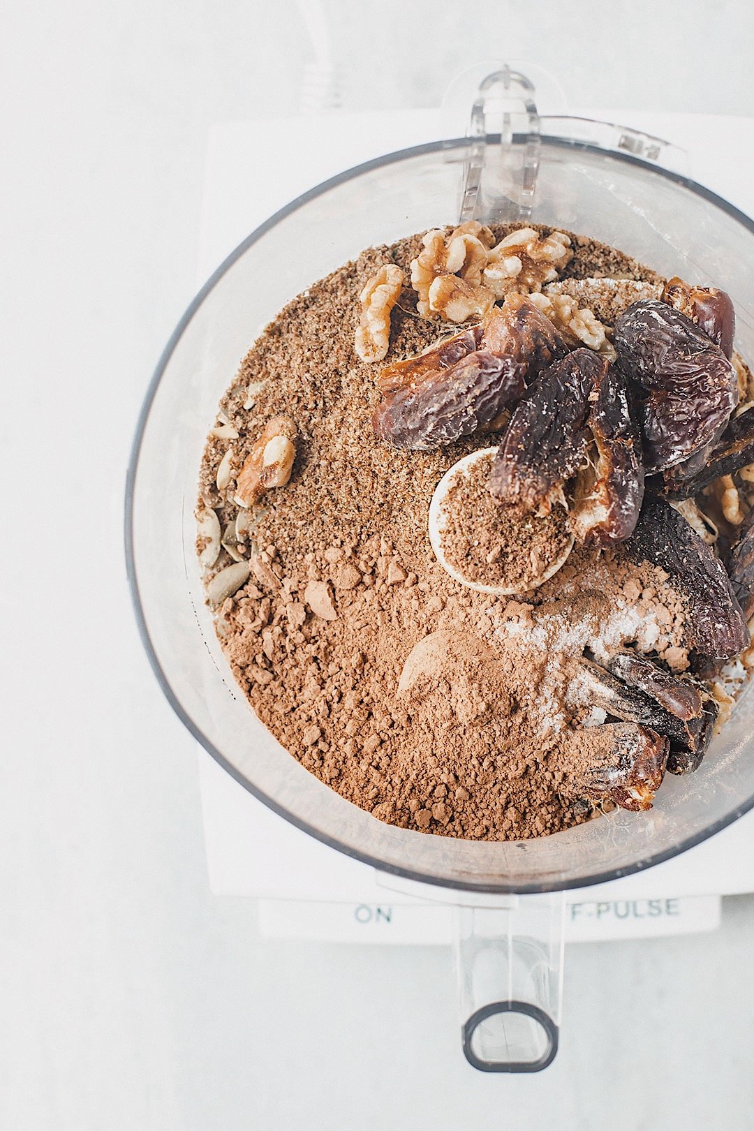 Vegan seed cycling brownie bite ingredients blending together in a food processor.