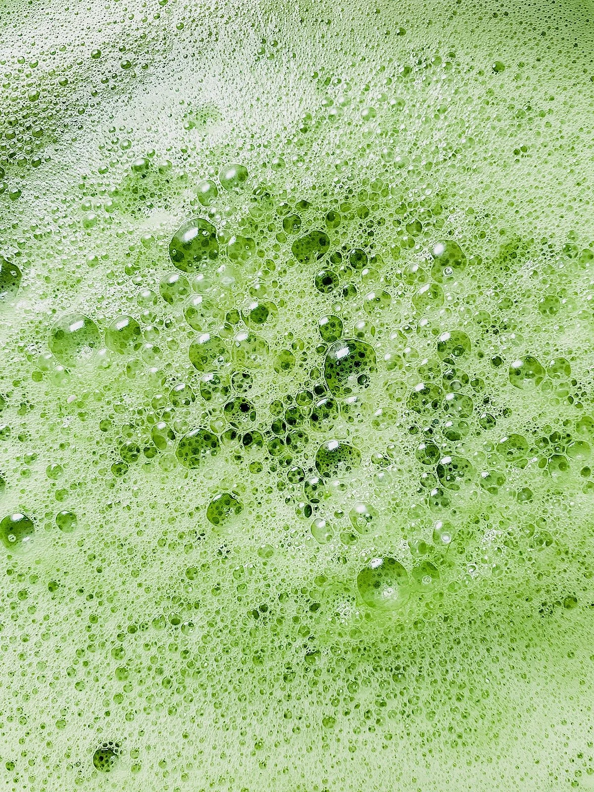 Close-up overhead shot of bright green juice showing frothy texture.