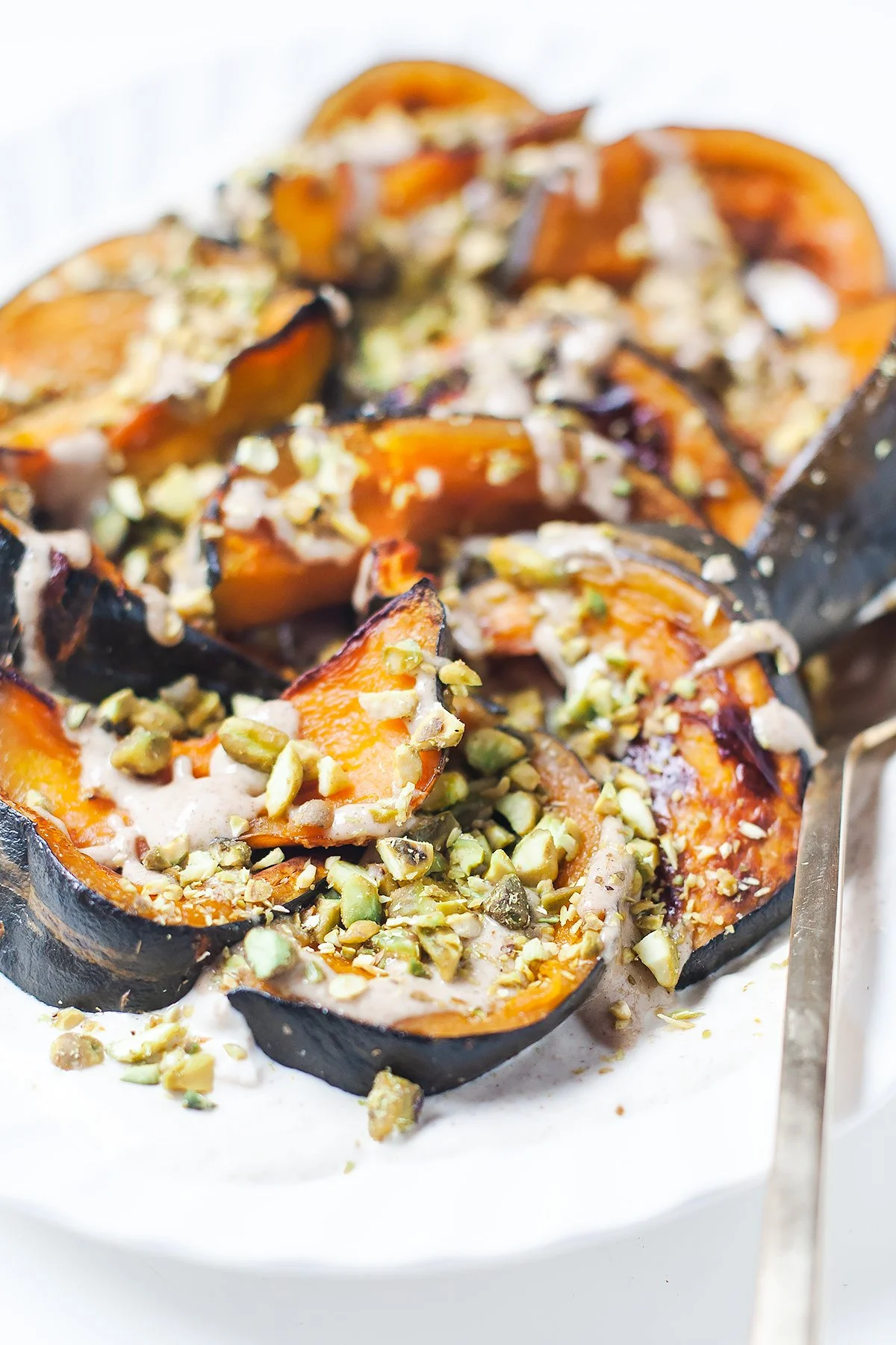 Roasted kabocha squash over tahini yogurt topped with salted pistachios.