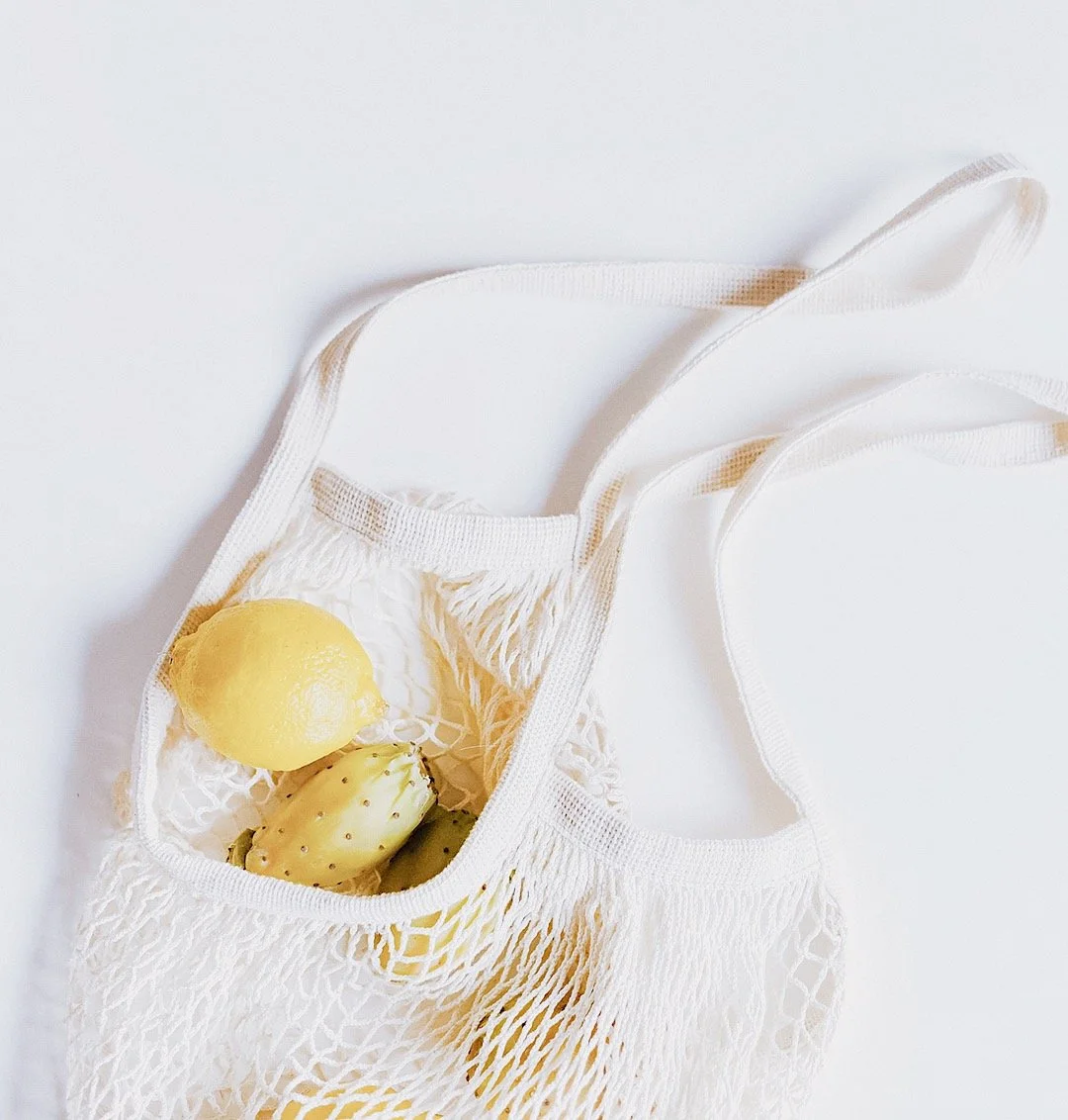 Fresh lemons in a reusable mesh tote — simple natural way to support stomach acid and healthy digestion.
