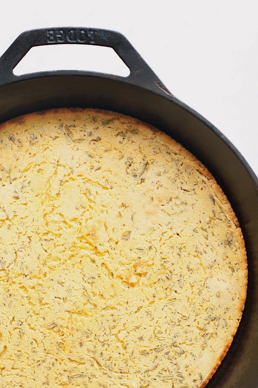 Golden socca flatbread cooking in a cast-iron skillet.
