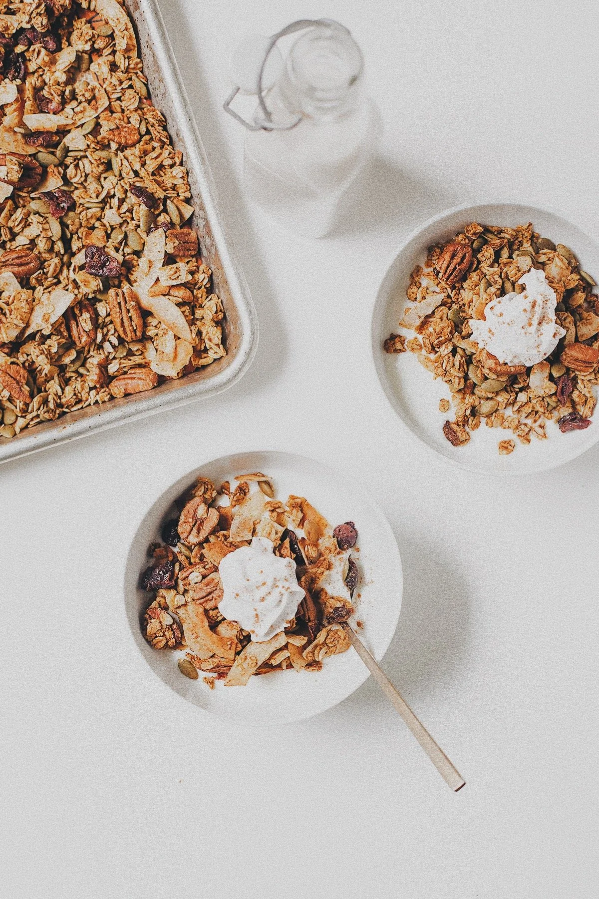 Pumpkin granola served in bowls alongside a tray of freshly baked granola.