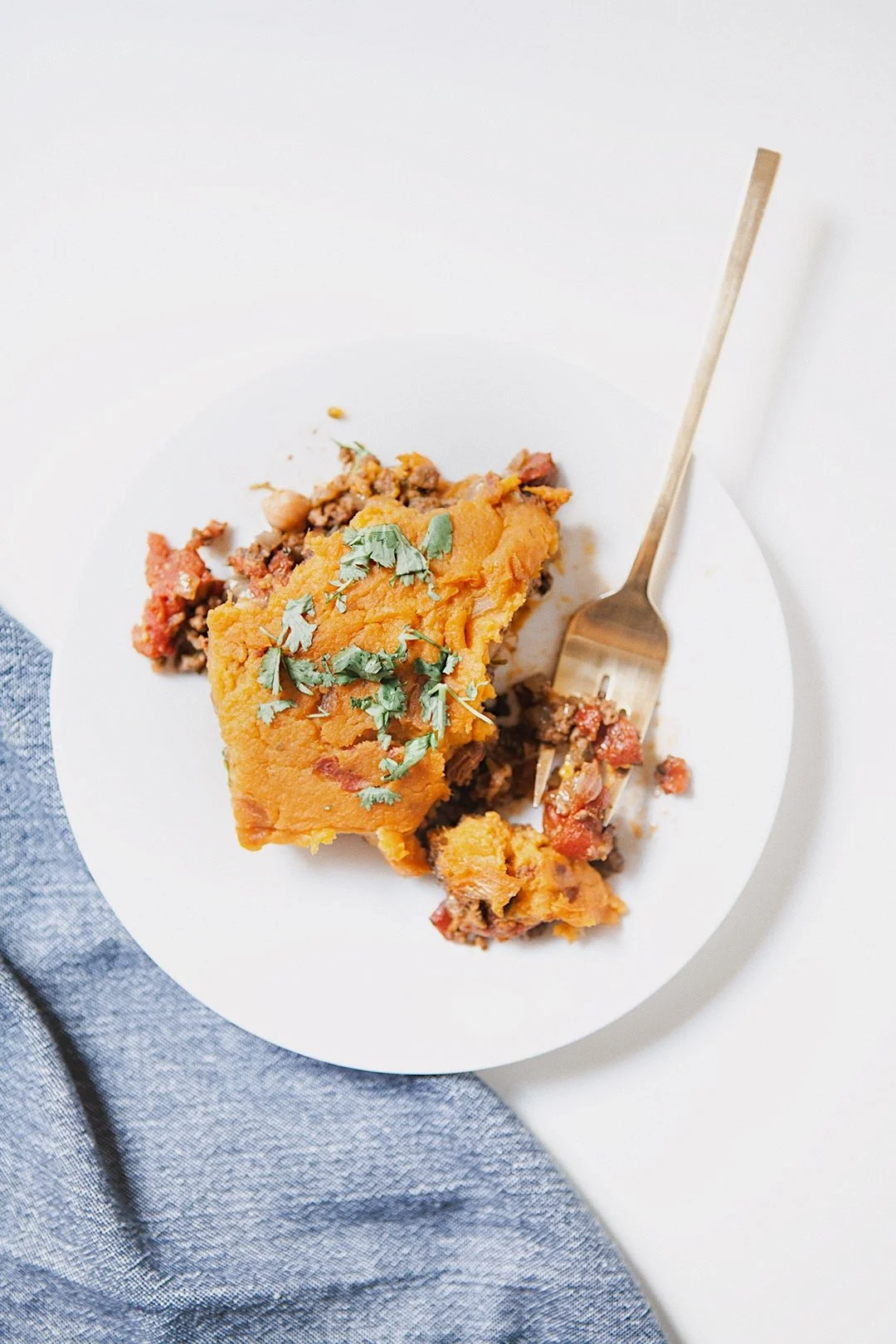Healthy Moroccan shepherd’s pie with sweet potato mash served on white plate with napkin.