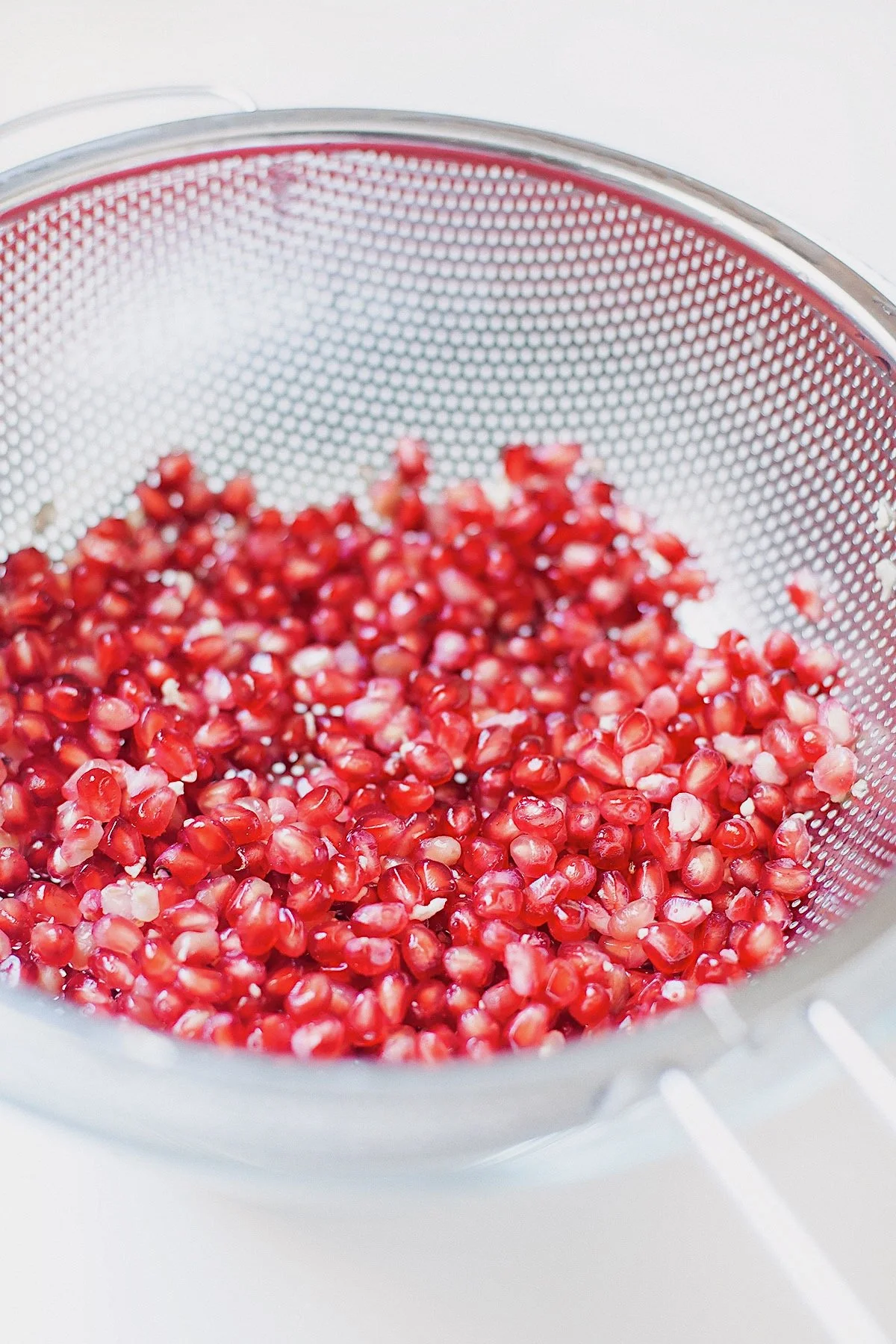Fresh pomegranate seeds in a fine mesh strainer.