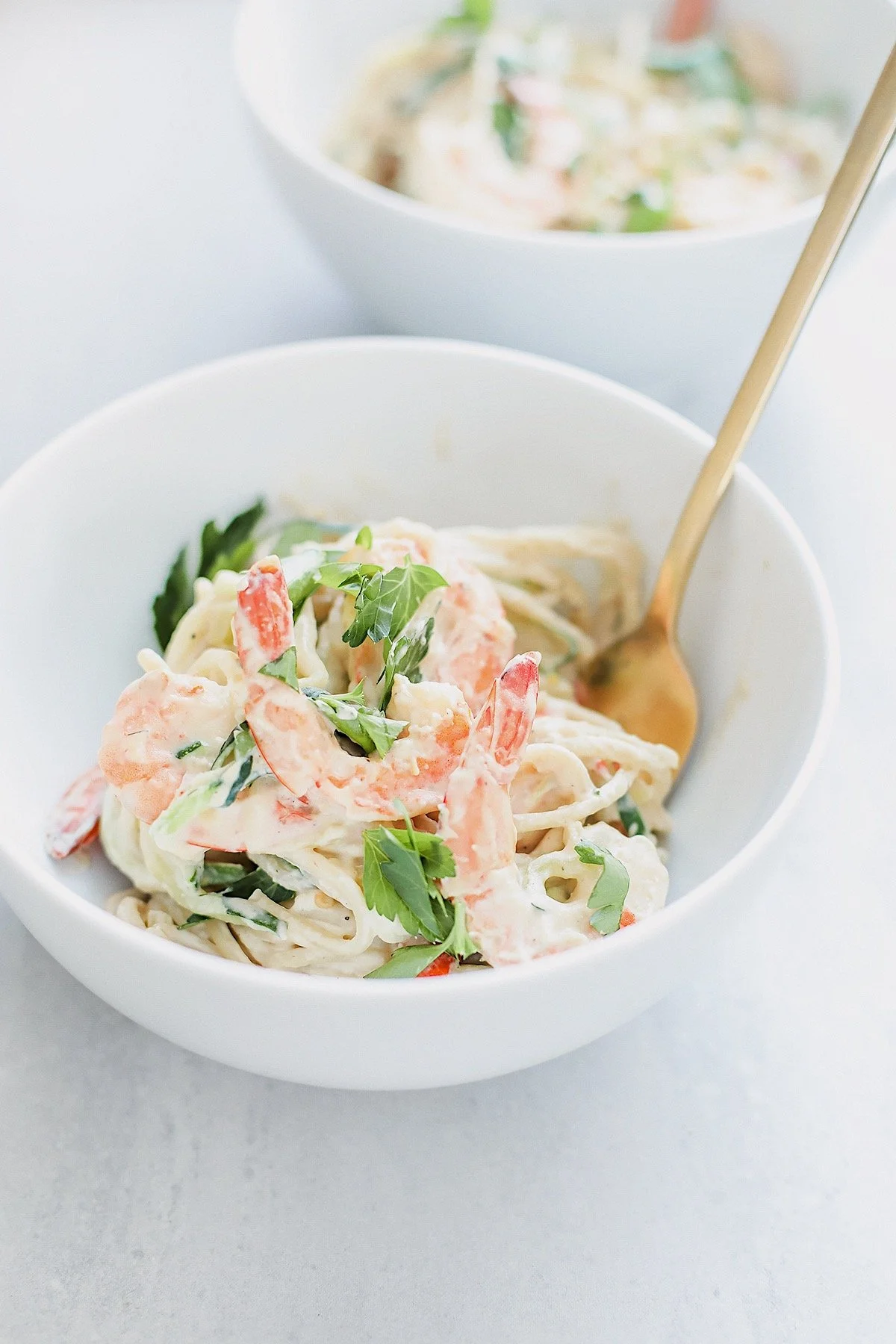 Healthy dairy-free shrimp pasta alfredo served in a white bowl.