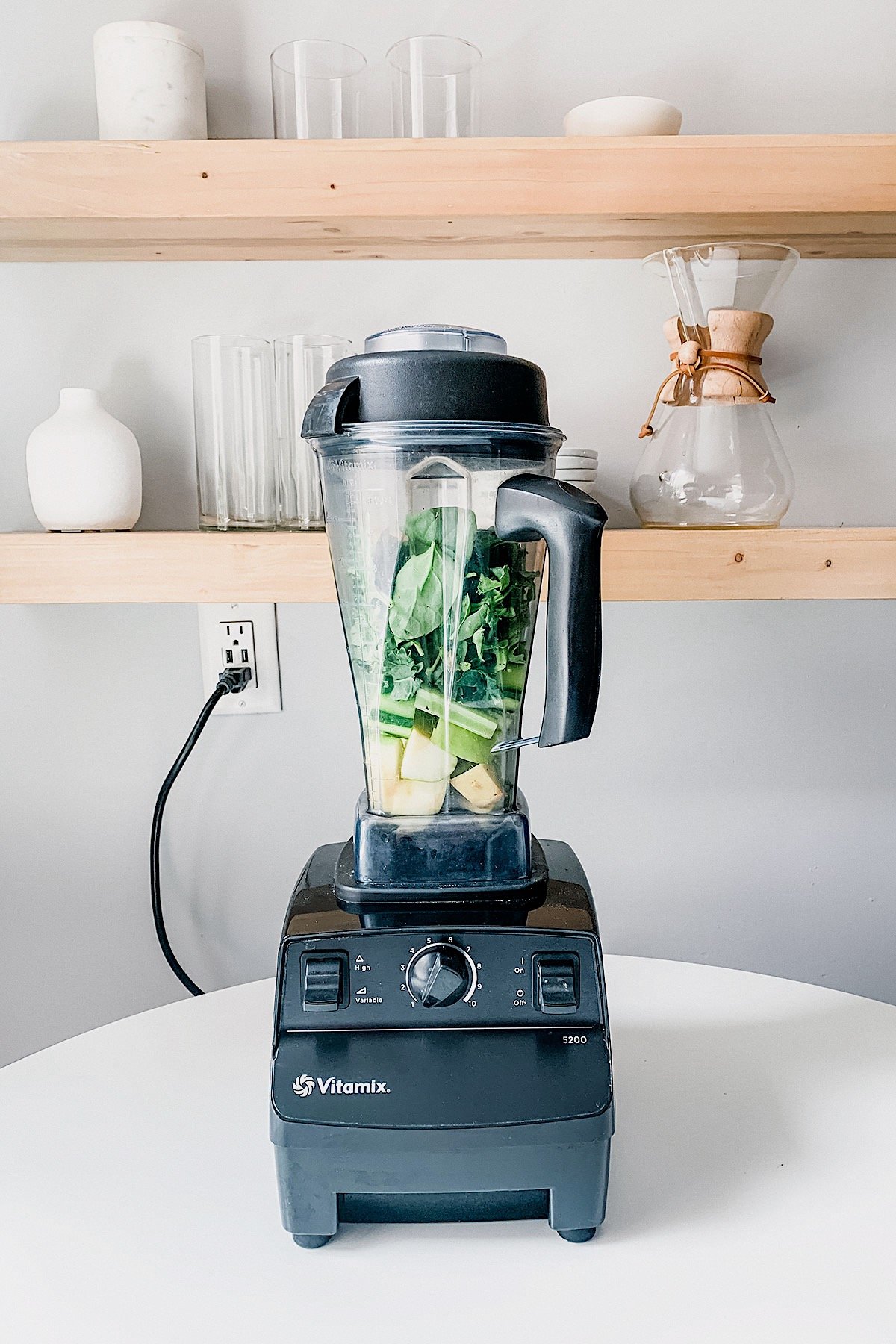 Blender on counter filled with blended green juice.