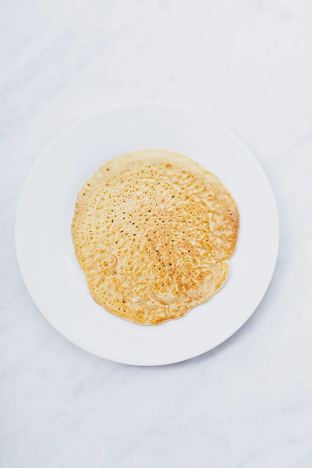 Baked chickpea socca flatbread on a white plate.