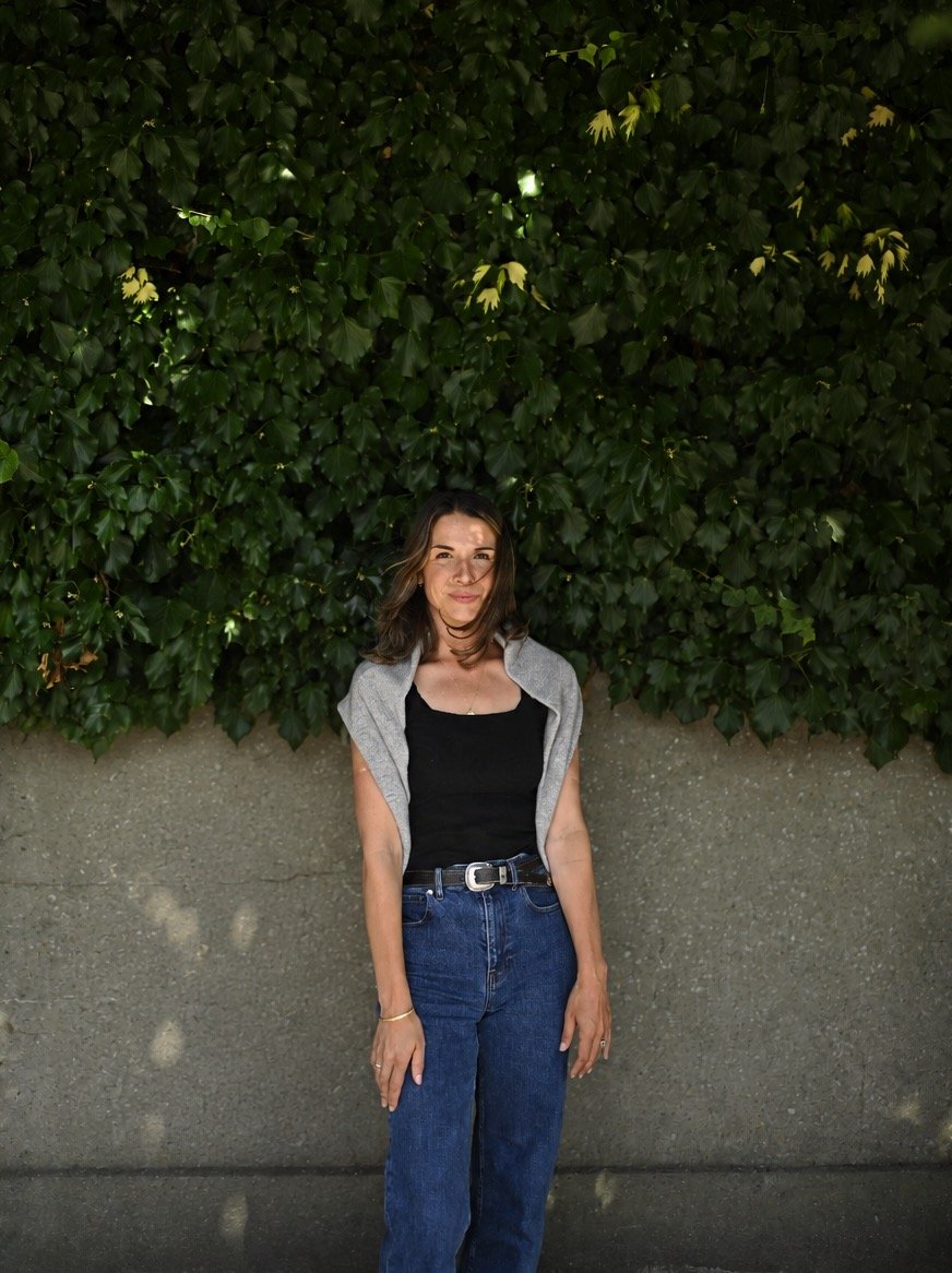 Ally Milligan, founder of Bye Bloat, standing outdoors in front of greenery.