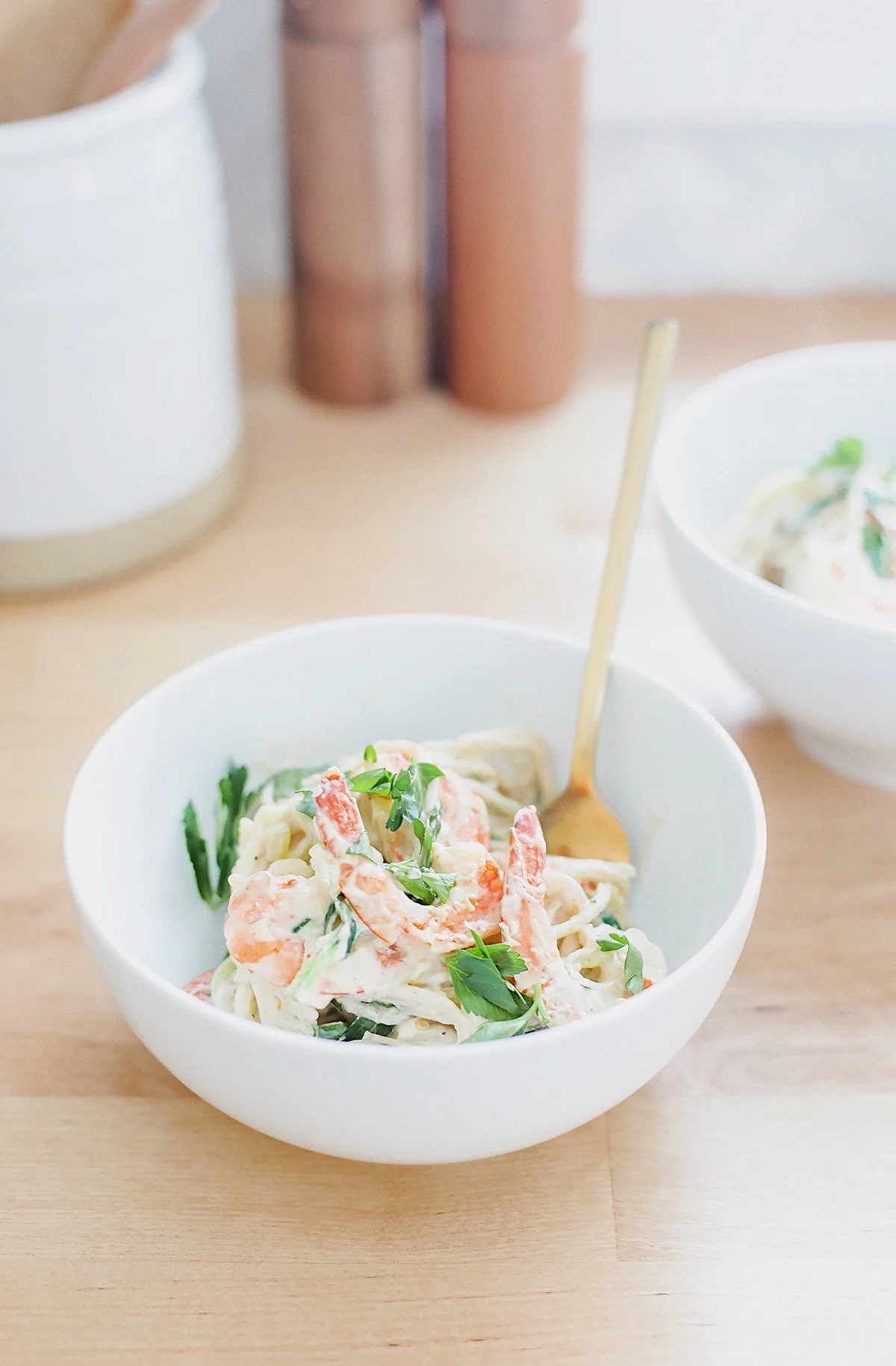 Creamy dairy-free shrimp fettuccine alfredo in a white bowl with zucchini noodles.