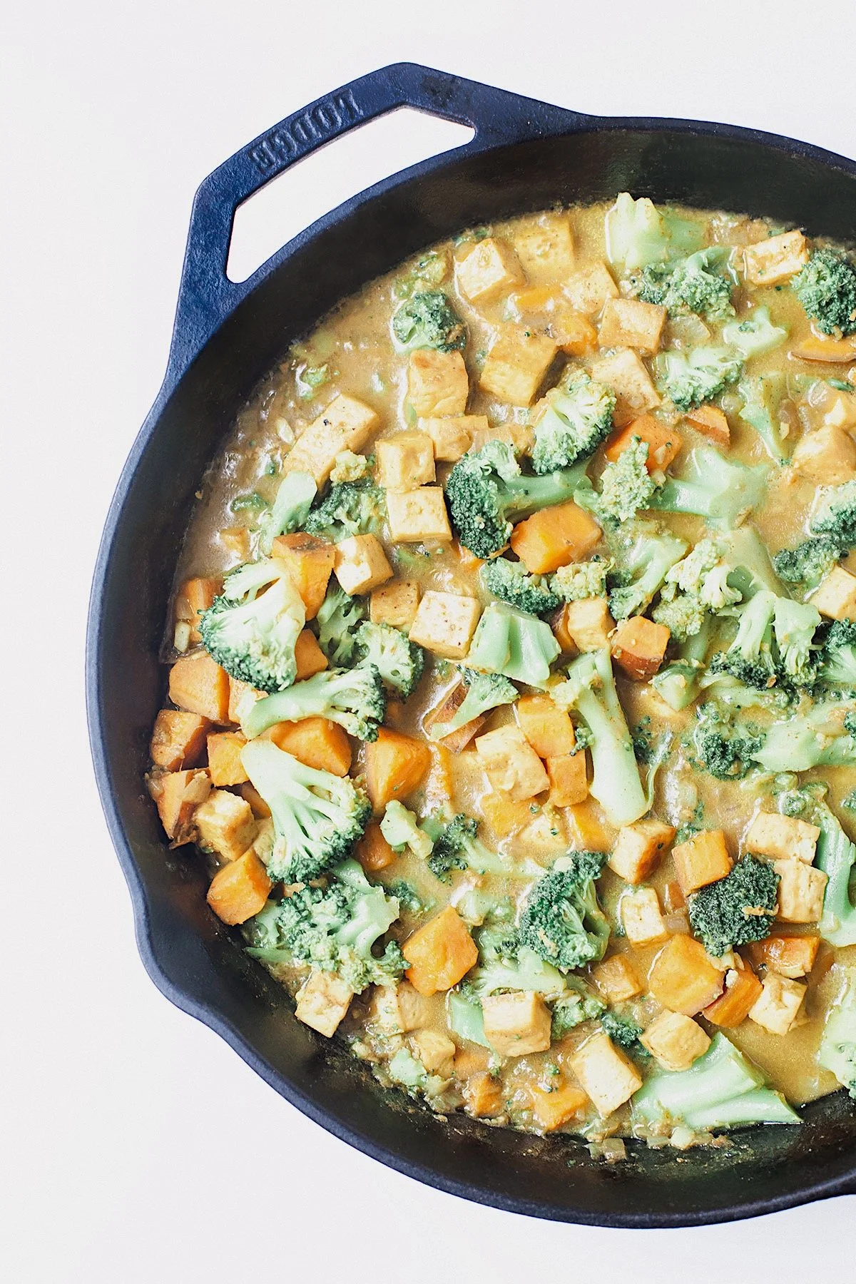 Overhead view of easy vegetable curry with broccoli, sweet potato, and tofu in a skillet.