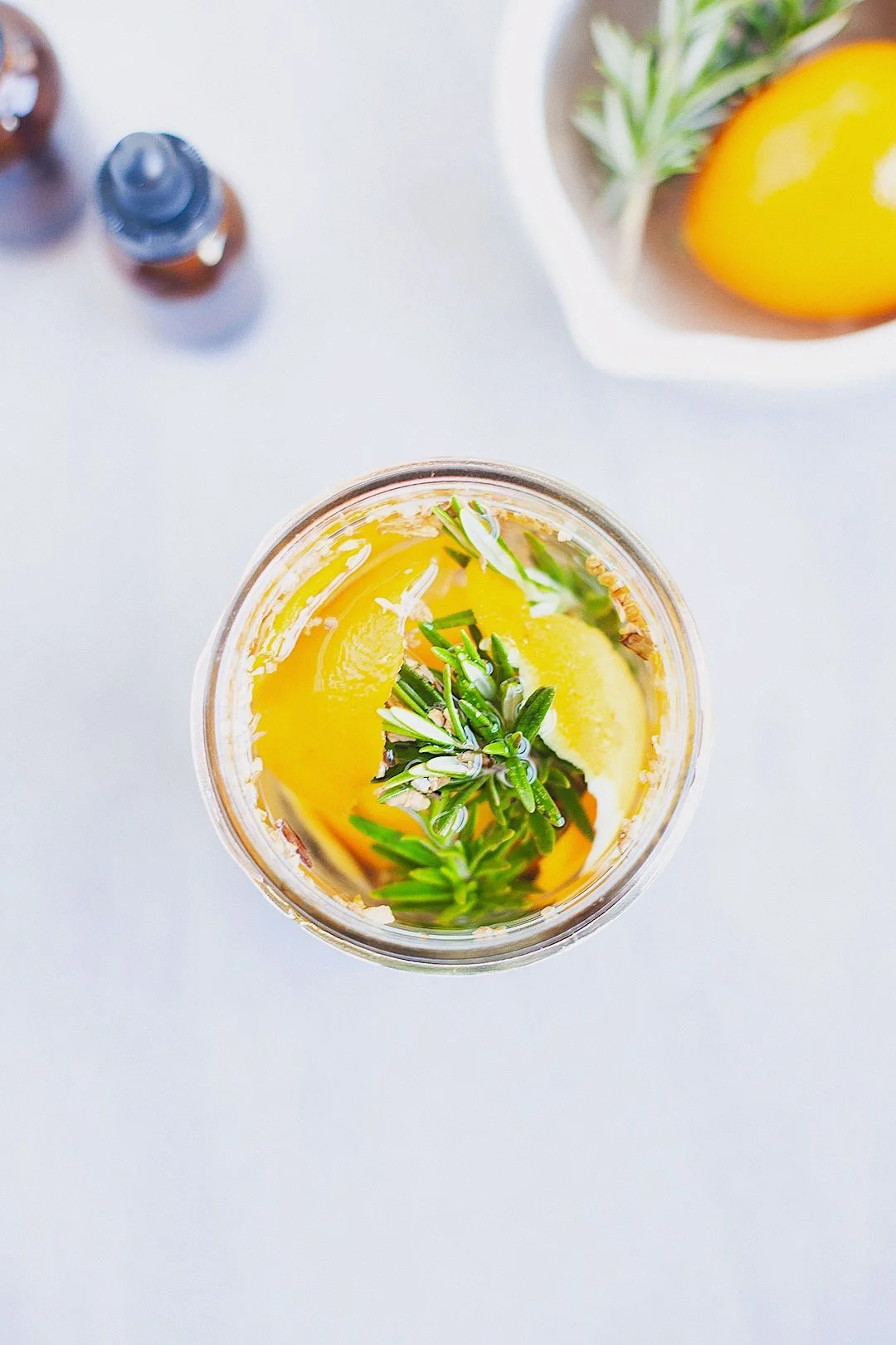 Top view of homemade digestive bitters with orange peel and herbs steeping in a jar.