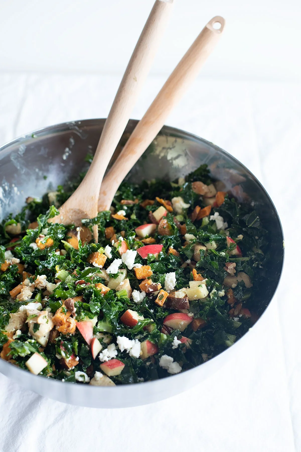 Close-up of fall kale and apple salad with apples, roasted sweet potatoes, pecans, chicken, and feta.