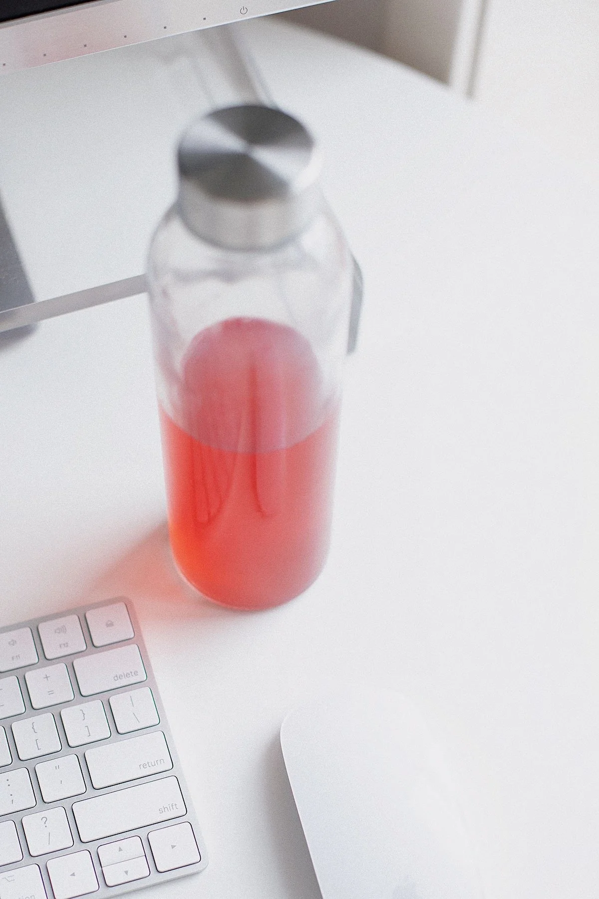 Homemade electrolyte drink in a glass bottle beside a computer keyboard.