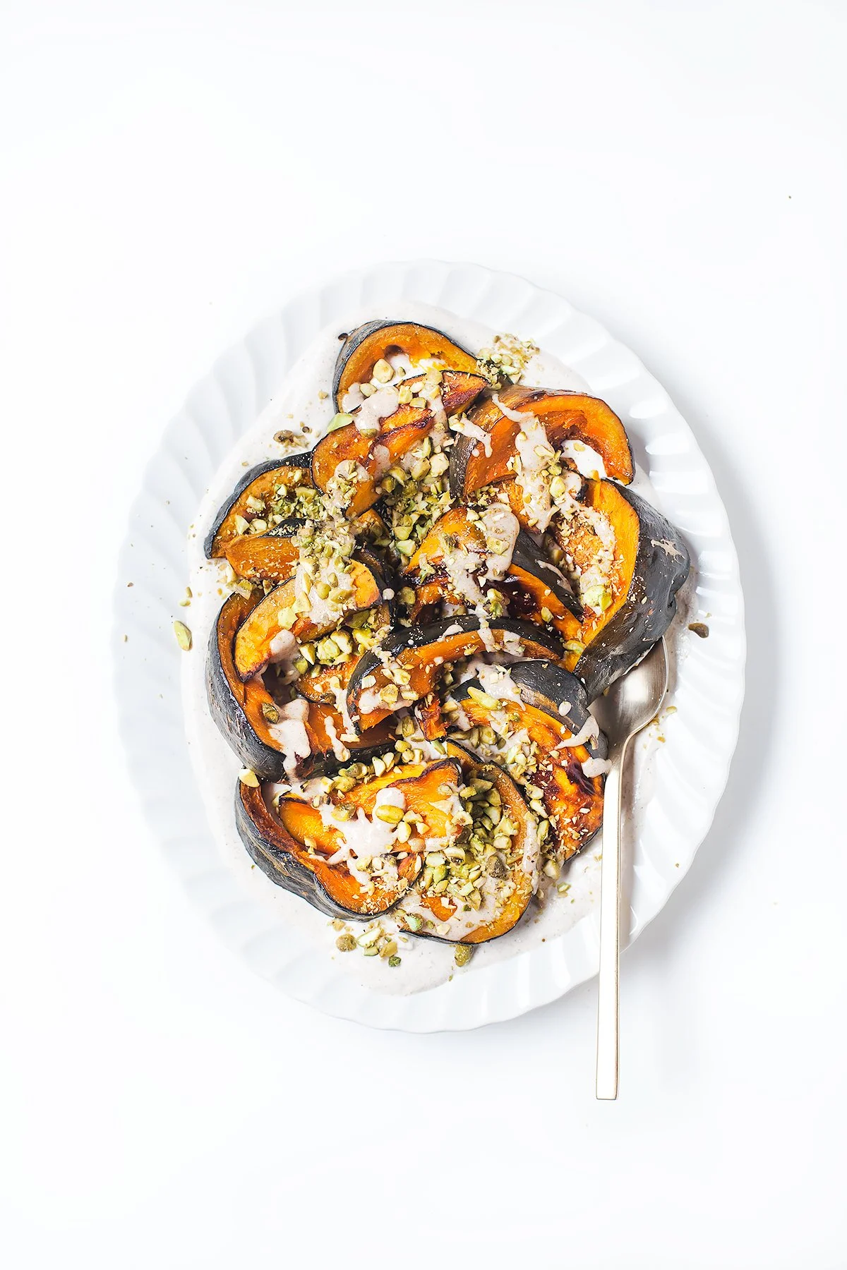 Roasted kabocha squash with spiced tahini yogurt and chopped pistachios.