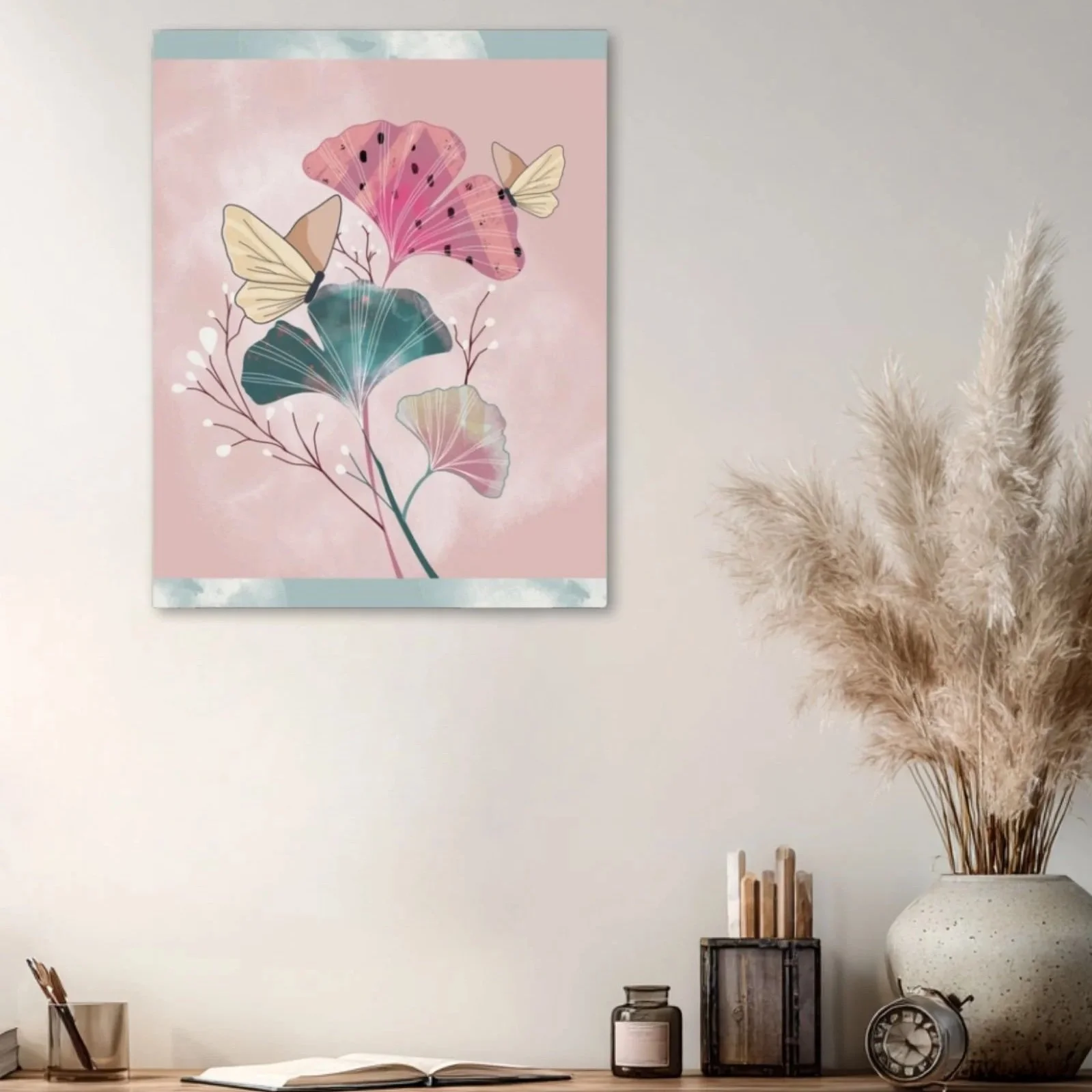 Botanical canvas wall art featuring butterflies and ginkgo leaves in blush tones, styled above a table with neutral decor and pampas grass.