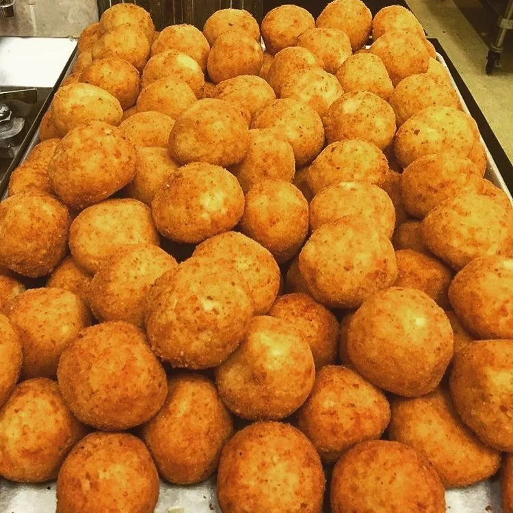 A large tray filled with golden-brown, crispy cheese balls.