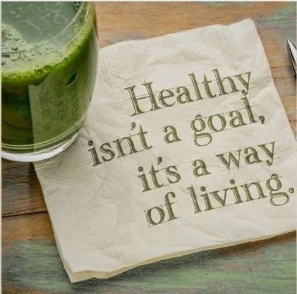 A glass of green smoothie next to a napkin with the quote 'Healthy isn't a goal, it's a way of living.'