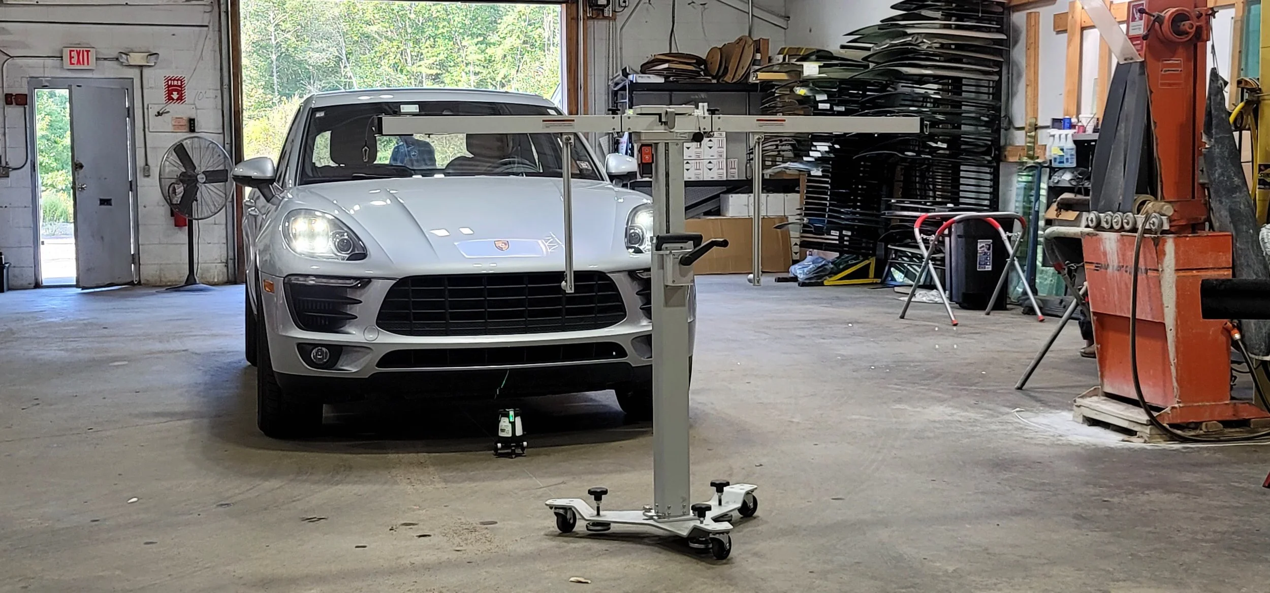 A silver sports car in a workshop with a car lift.