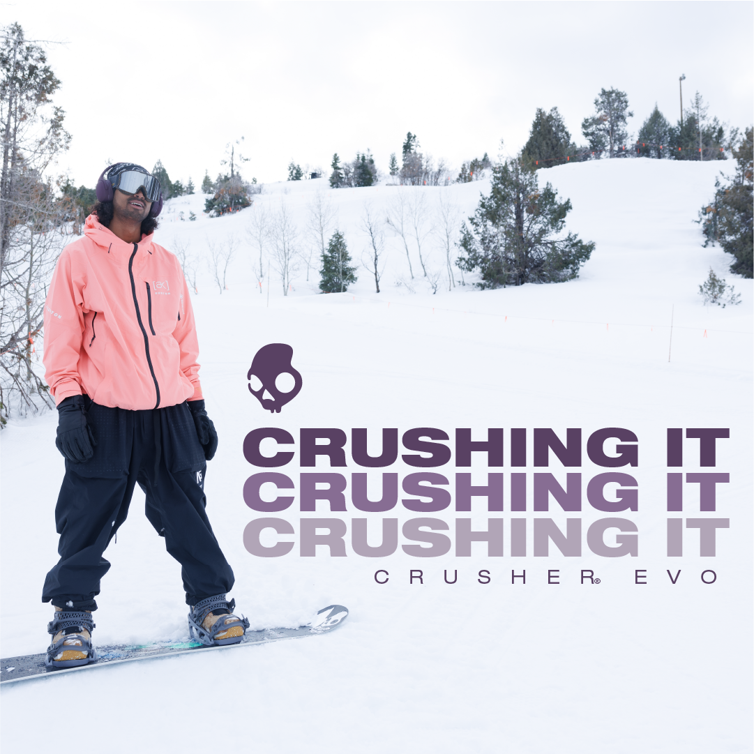 A person snowboarding on a snow-covered slope with trees in the background. The person is wearing a pink jacket, black pants, gloves, and snow goggles. Overlaid on the image is the text "CRUSHING IT" repeated three times in bold purple letters, accom