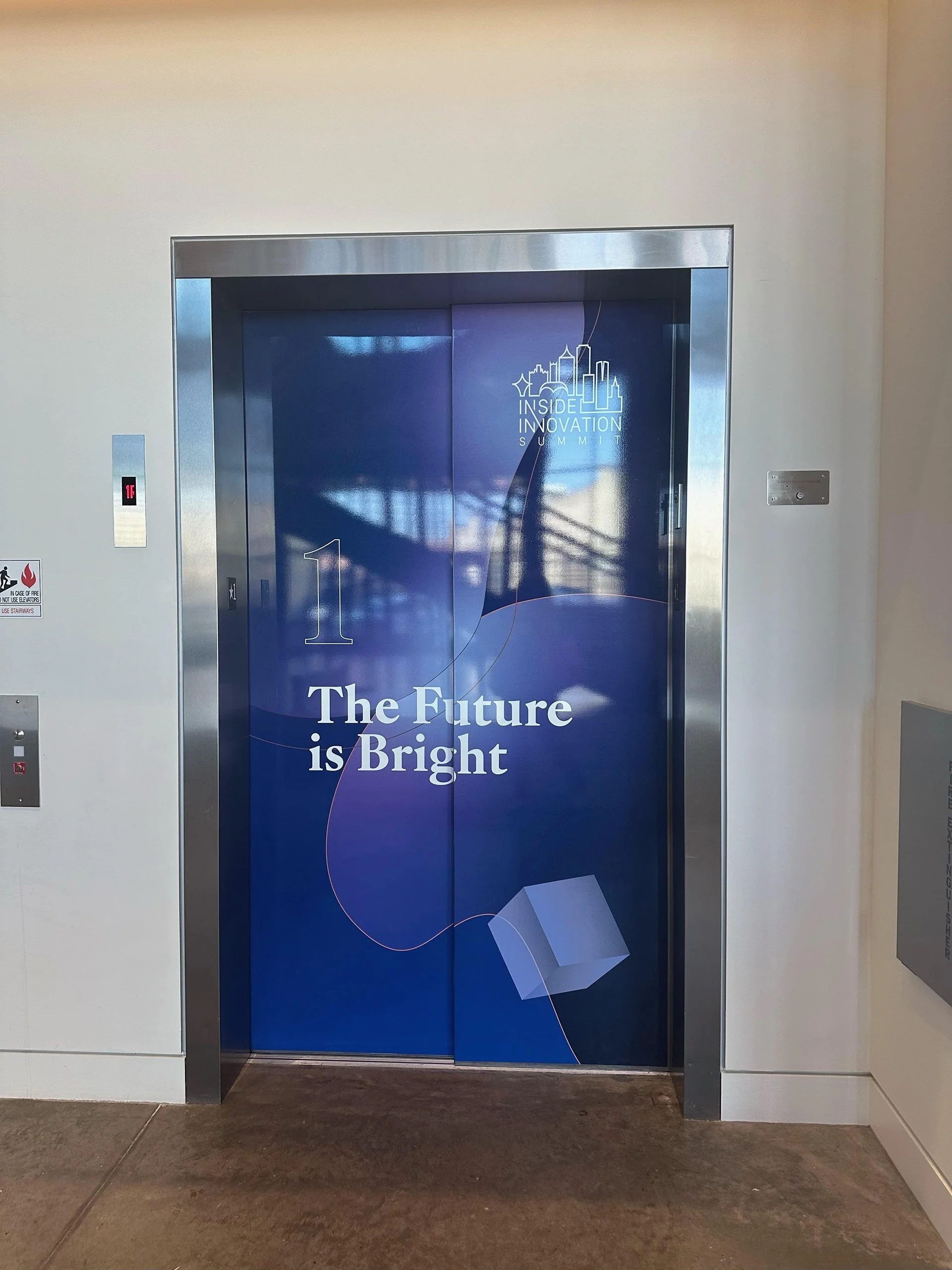 Elevator door with a blue graphic design, including the text 'The Future is Bright' and 'Inside Innovation Summit'.