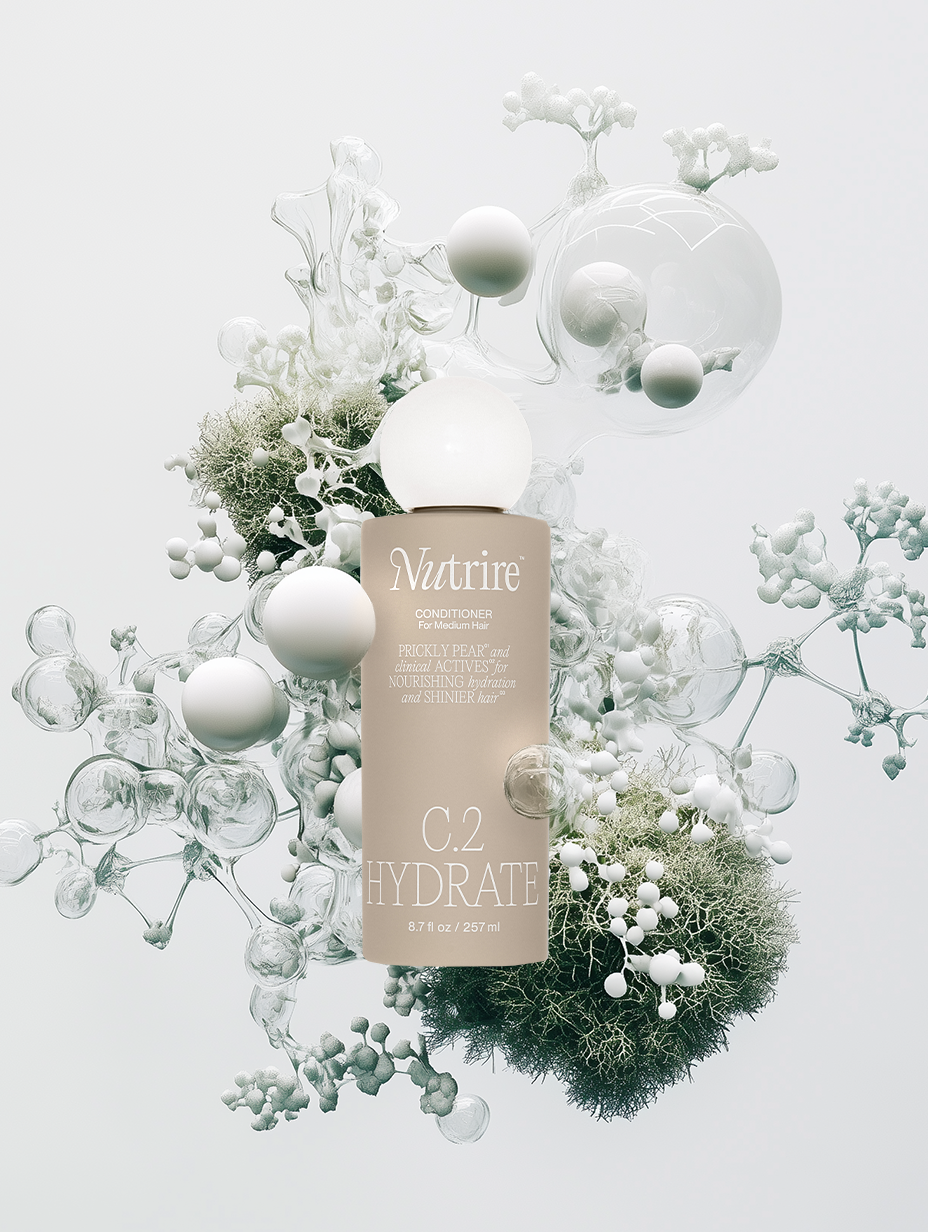A beige bottle of Nutriire C.2 Hydrate conditioner for medium hair surrounded by abstract white and clear spherical and coral-like structures.