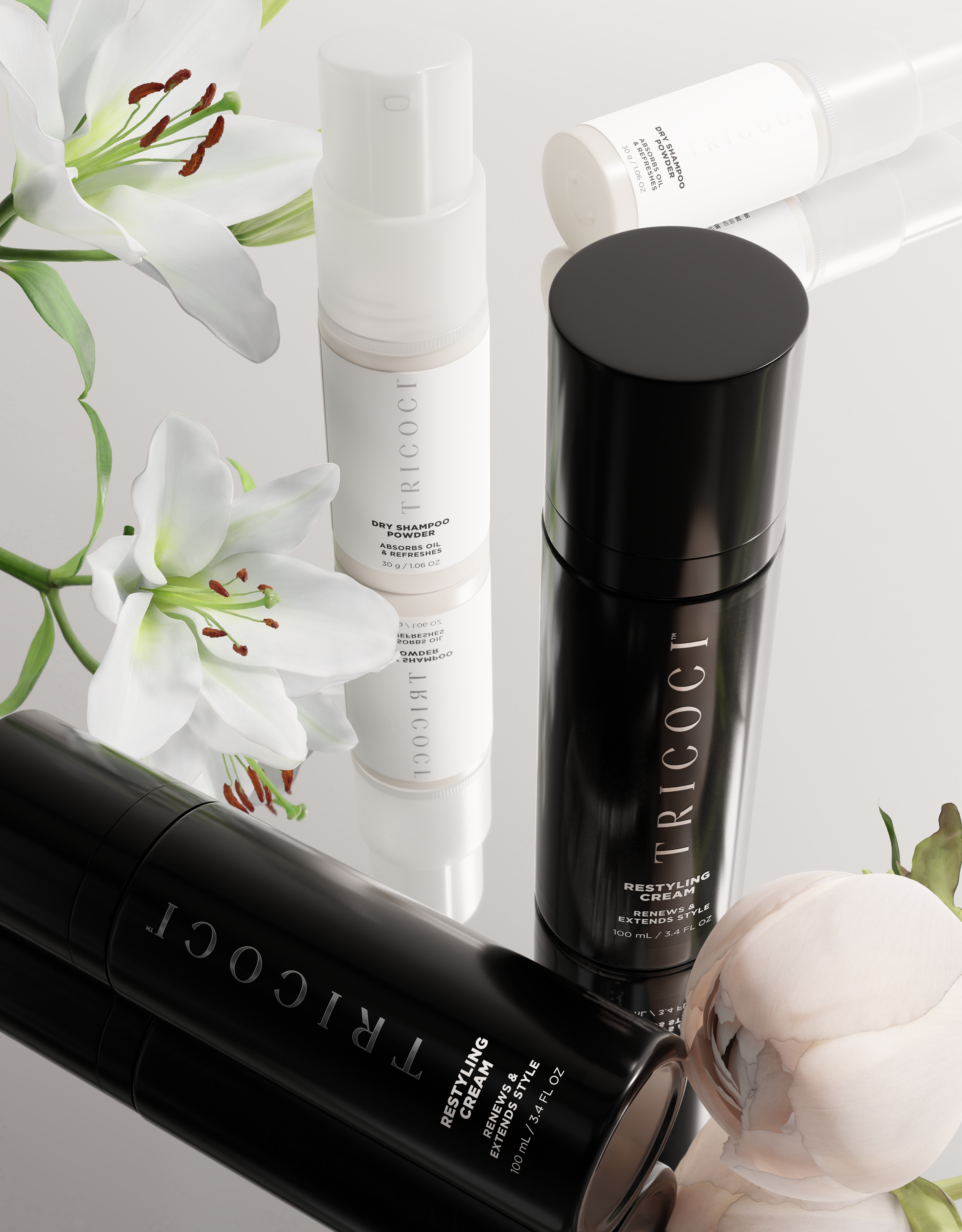 Three Tricoci beauty products: a white dry shampoo powder, a black styling cream, and a black restyling cream, accompanied by white lilies and a pink peony on a reflective surface.