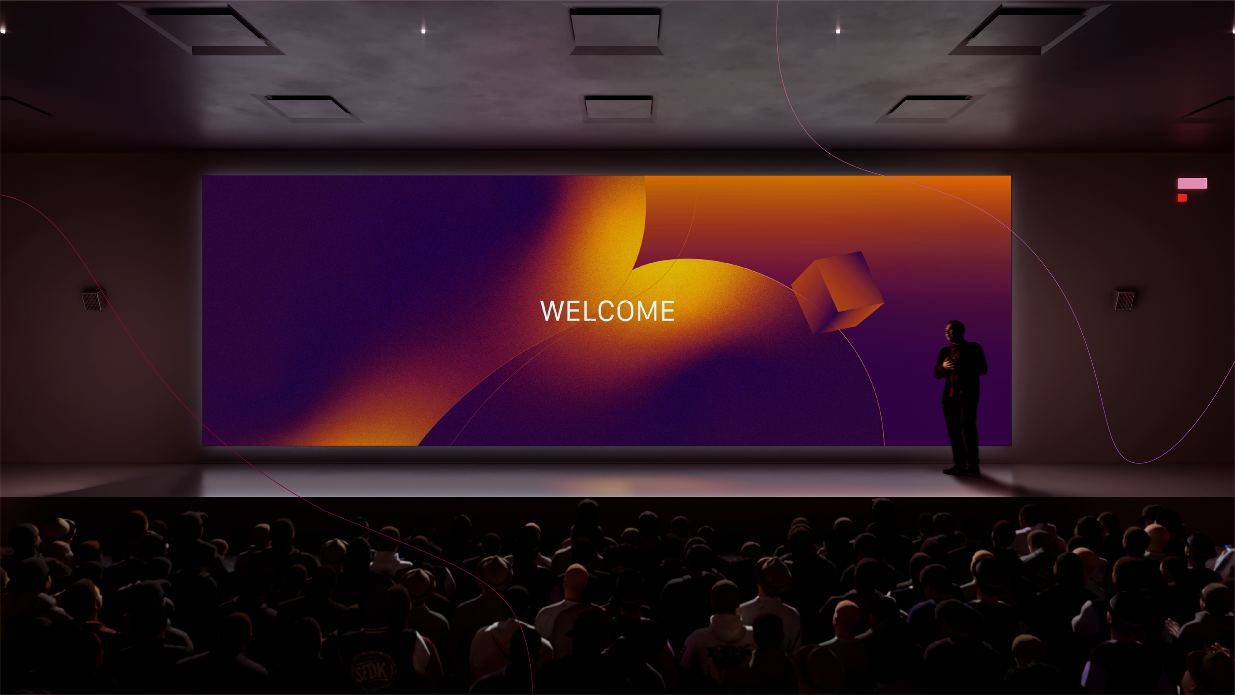 A person standing on a stage next to a large screen with the word 'WELCOME' displayed and a colorful abstract background, audience members are visible in the foreground.