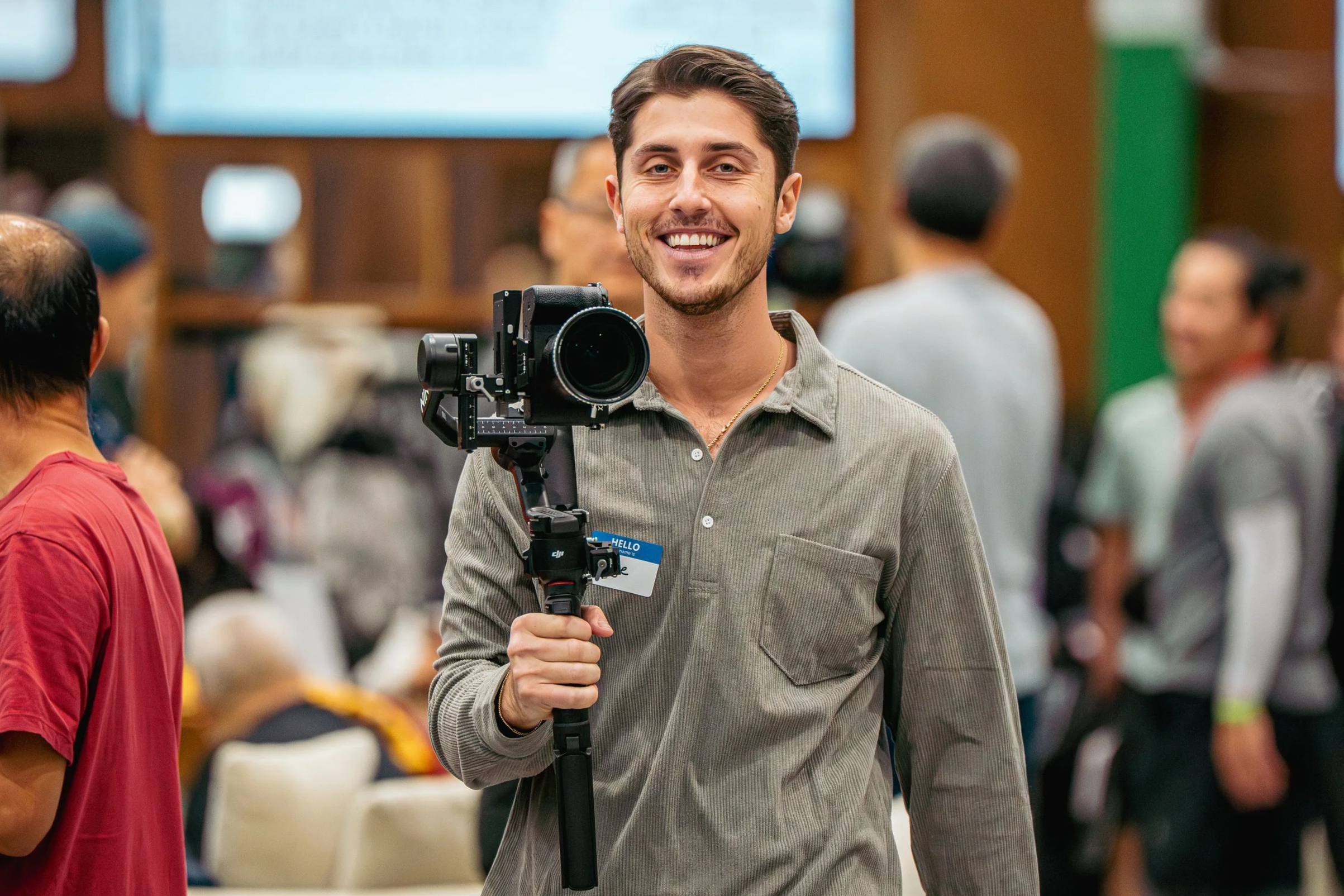 People dining on a rooftop deck with string lights, outdoor heaters, and boats docked in the marina at dusk.