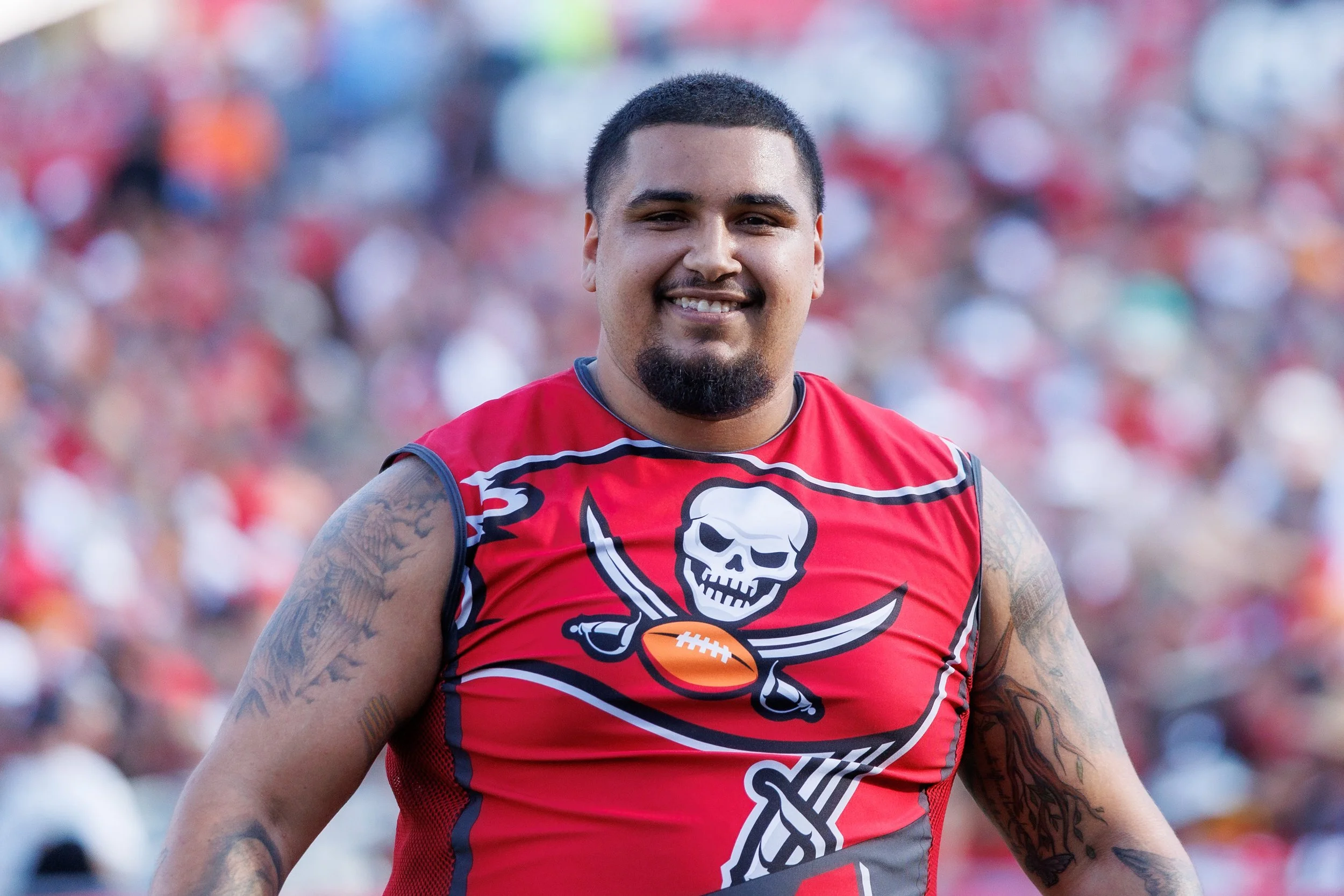 Coach BG wearing a Tampa Bay Buccaneers Stunt Team uniform, smiling on the field.
