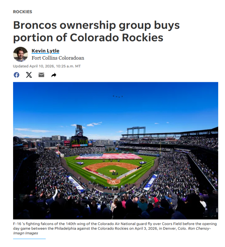 Coors Field a baseball stadium filled with spectators during daytime, with a clear blue sky and a large American flag displayed on the field, yearning to be supplied with great bus service.