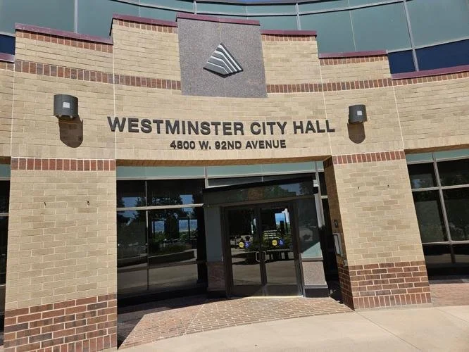 Facade of Westminster City Hall building with brick exterior, glass doors, and signage displaying its name and address, 4800 W. 92nd Avenue.