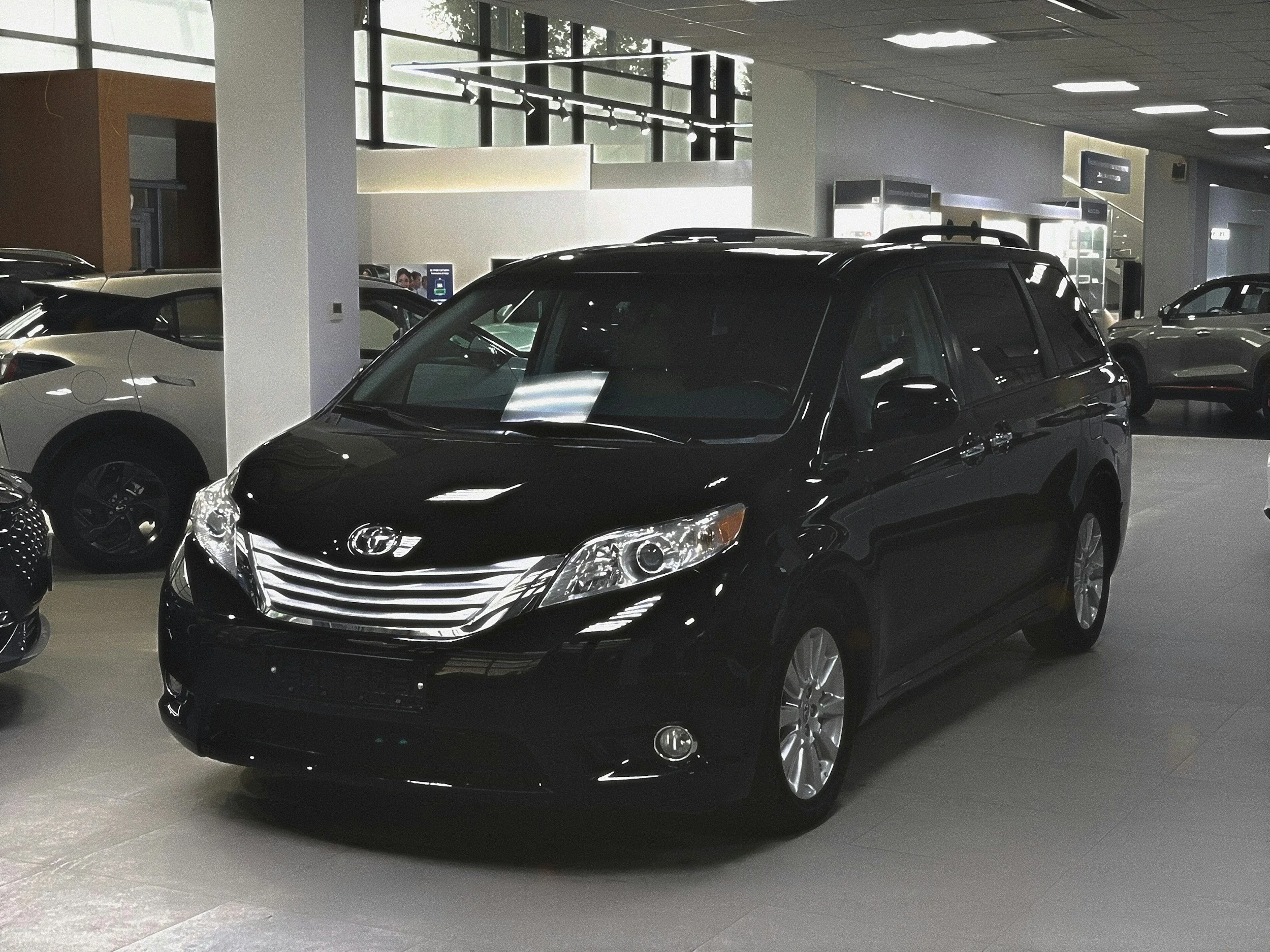 A black Hyundai SUV parked inside a car dealership with other vehicles visible in the background.